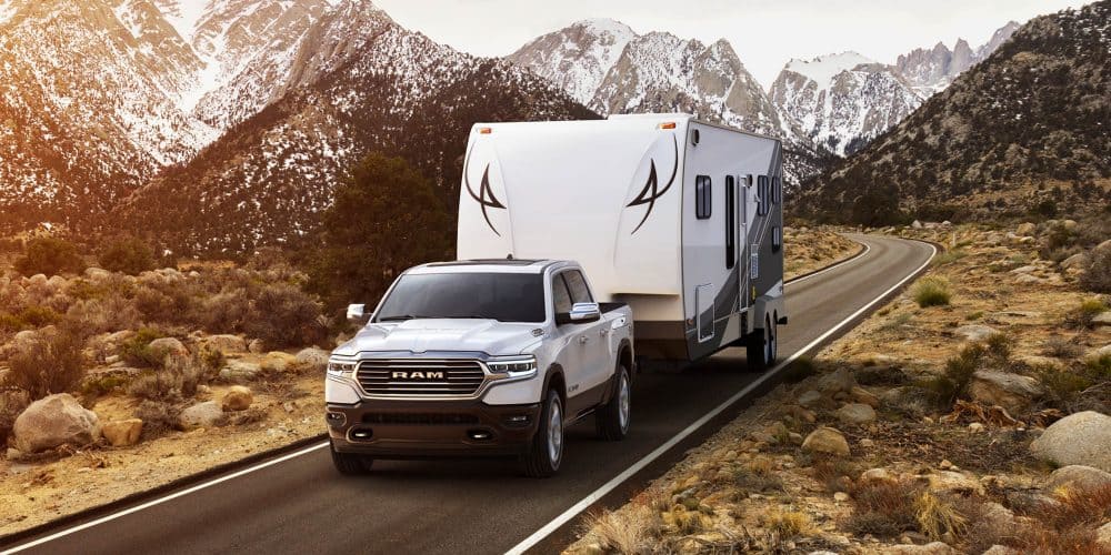White 2019 Ram 1500 towing trailer with snowy mountains in background