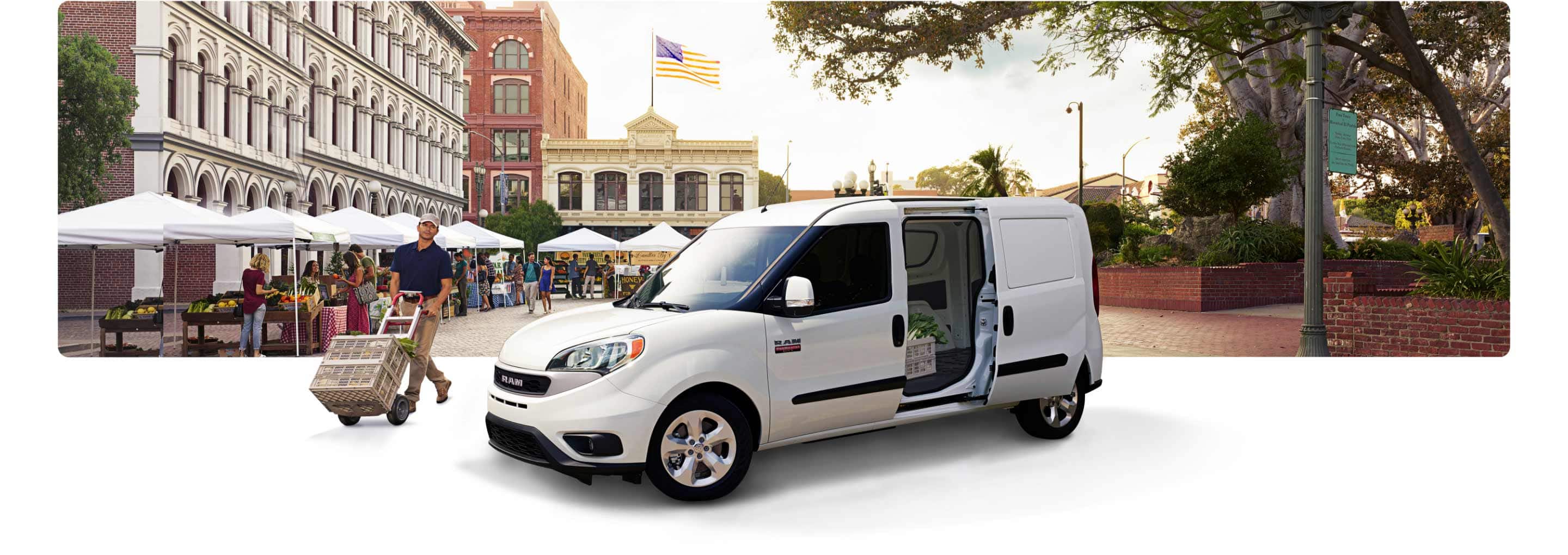 The 2021 Ram ProMaster City Cargo Van parked at an outdoor market with its driver-side rear door open.