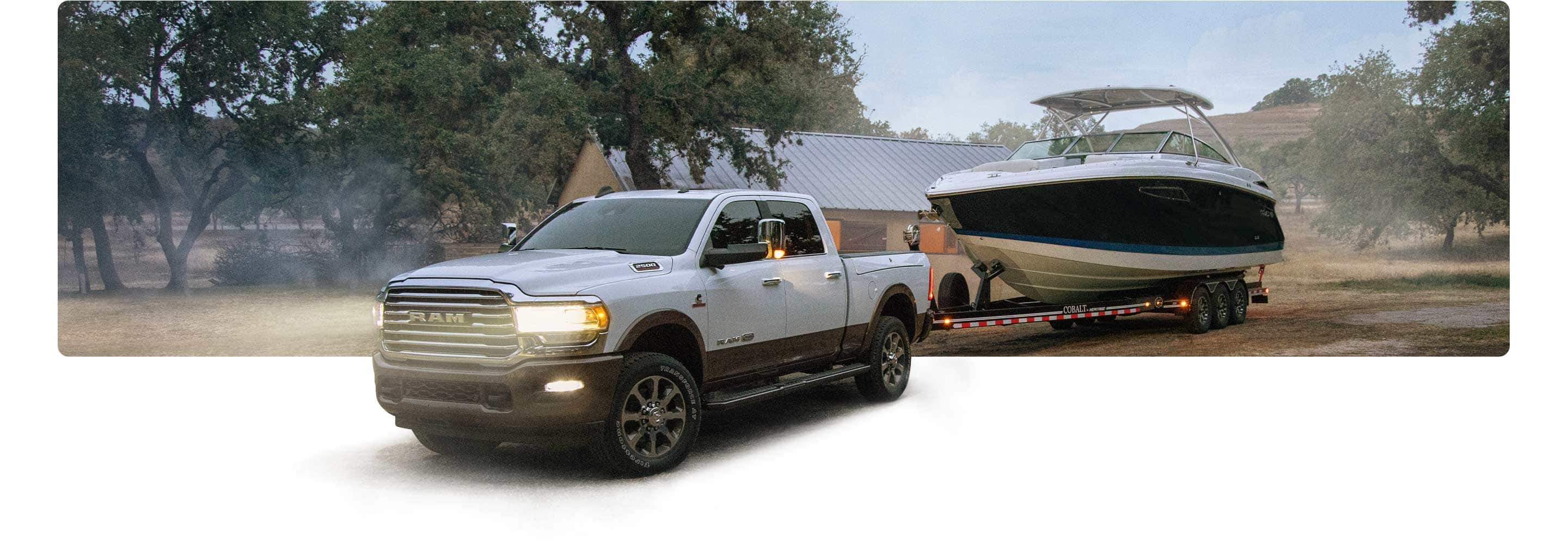 The 2021 Ram 2500 towing a boat on a dirt road.