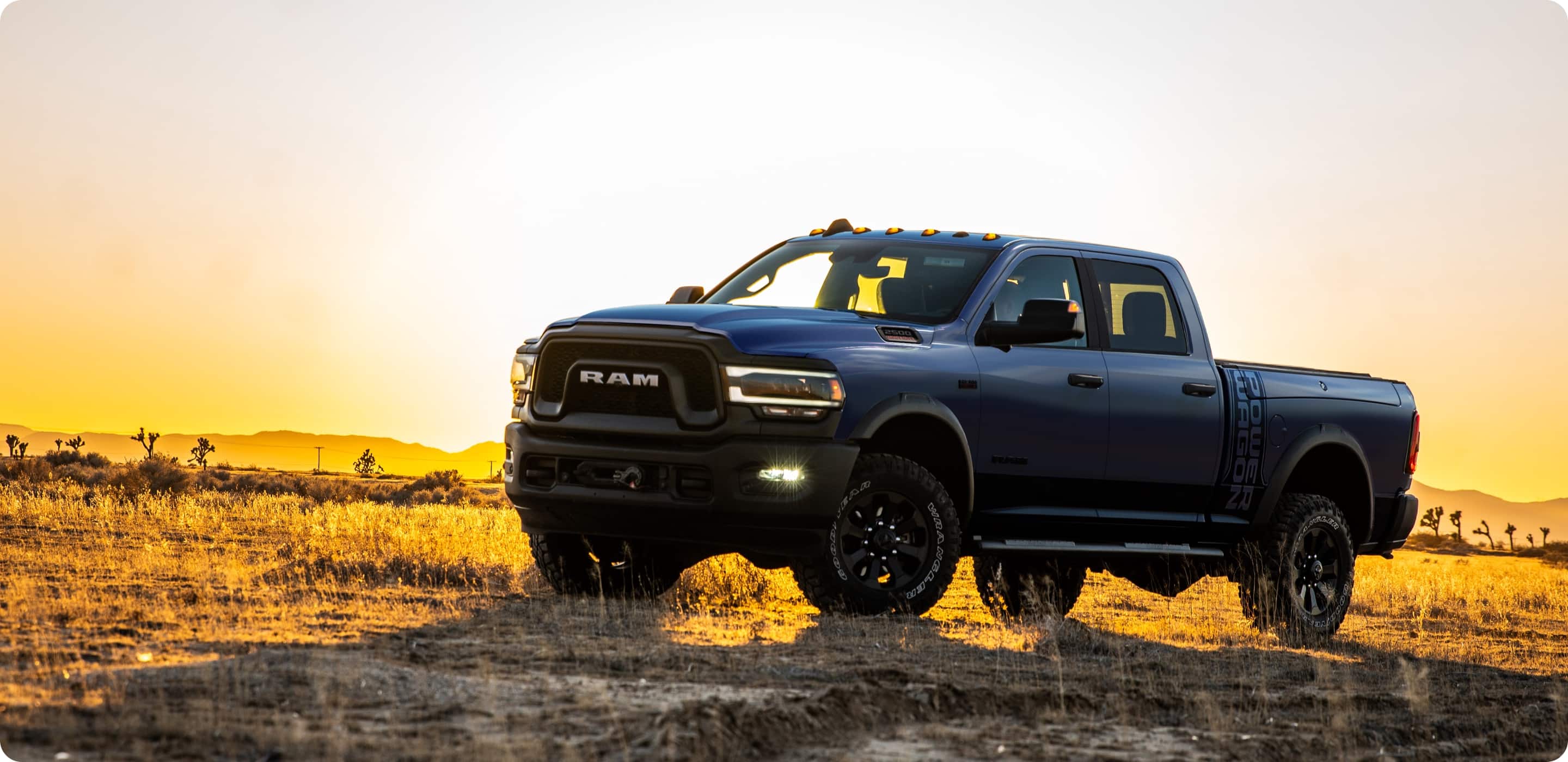 Display A 2021 Ram 2500 Power Wagon parked on a field that is bathed in golden light at sunset.