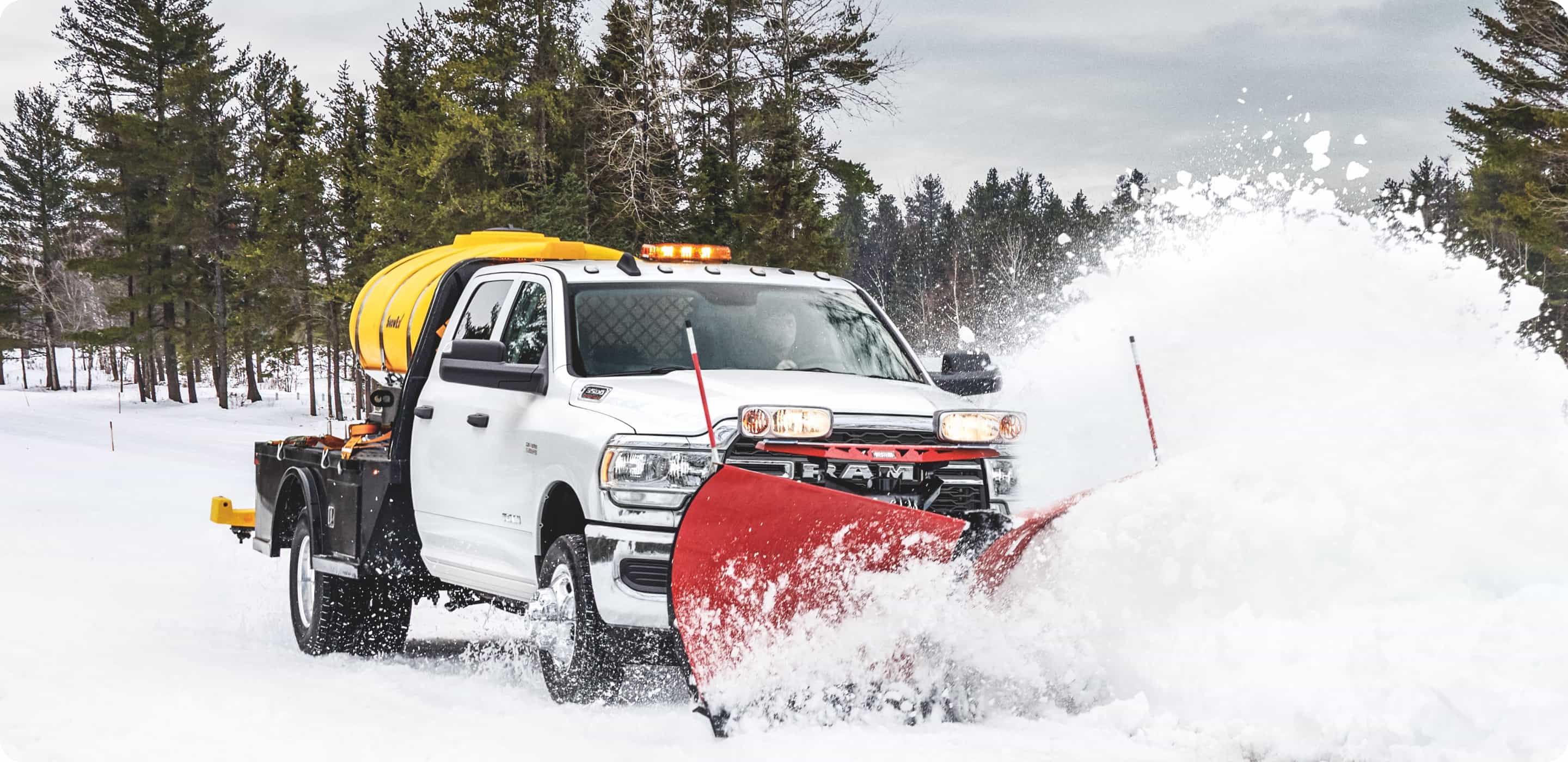 Display A 2021 Ram Chassis Cab with a snowplow upfit being driven through fresh snow.