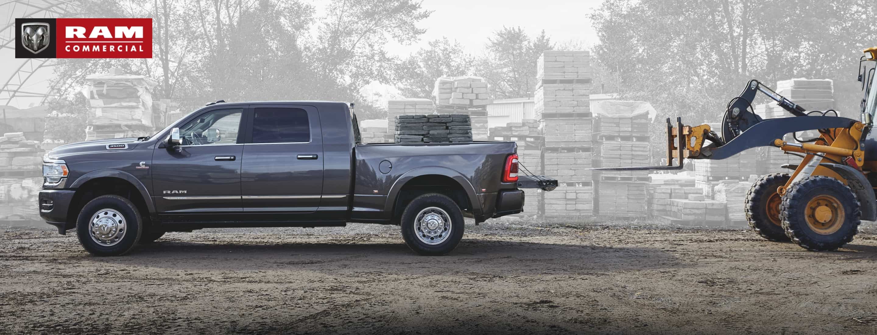 A 2021 Ram 3500 Limited Mega Cab 4x4 with its tailgate open, it's pickup box filled with paving stones that were just loaded in by a forklift. The Ram Commercial logo.