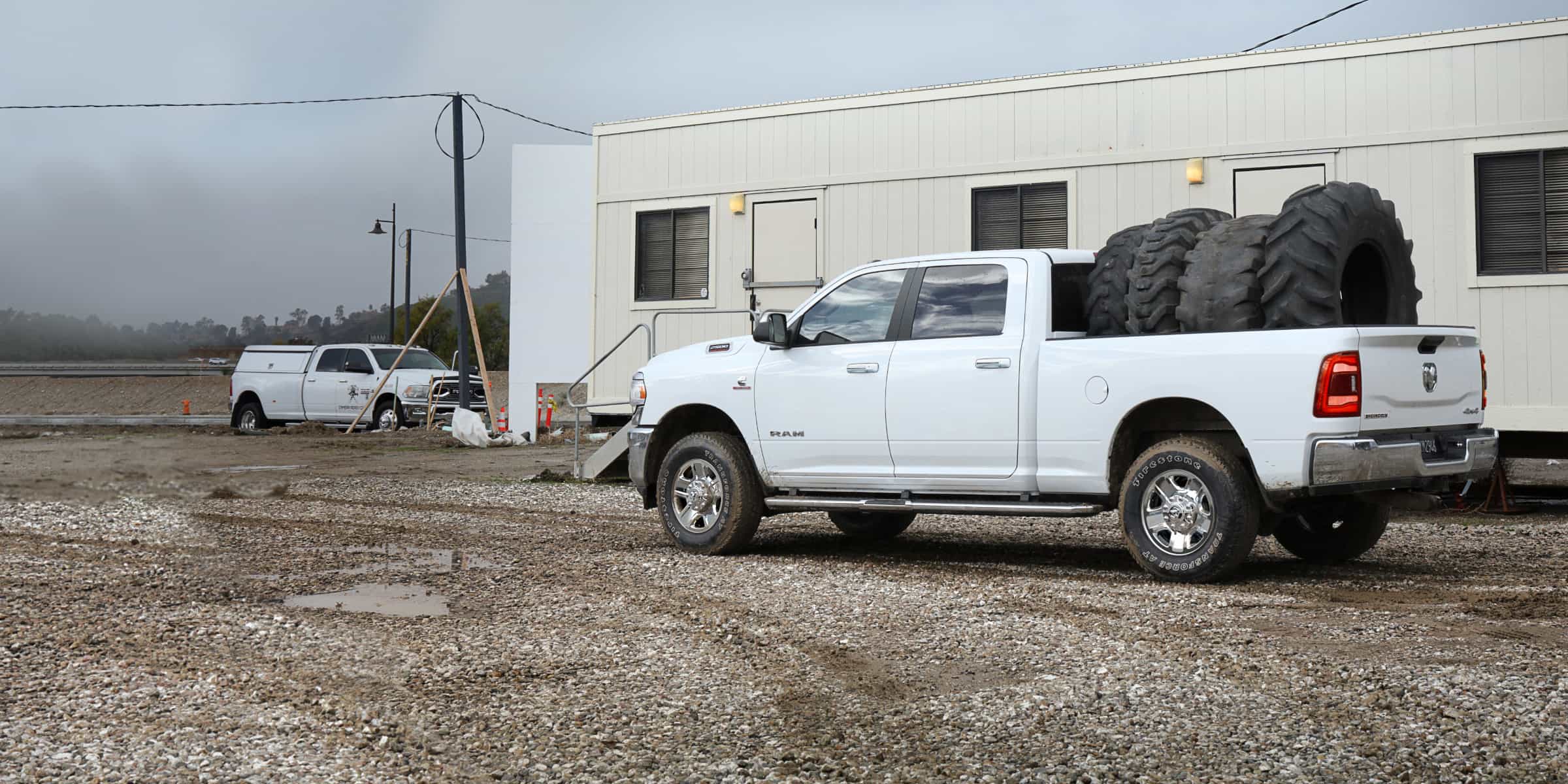 A white 2021 Ram 2500 with its bed filled with four oversized tires.