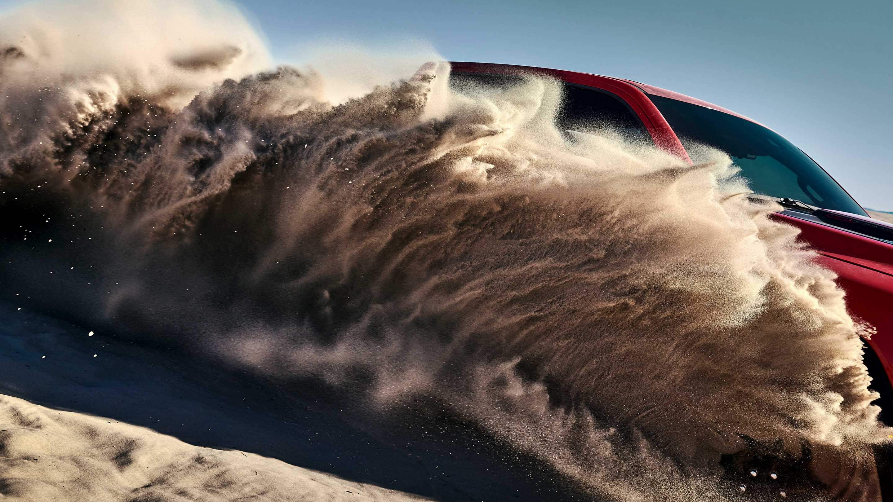 The 2021 Ram 1500 TRX churning up a cloud of sand from its wheels.