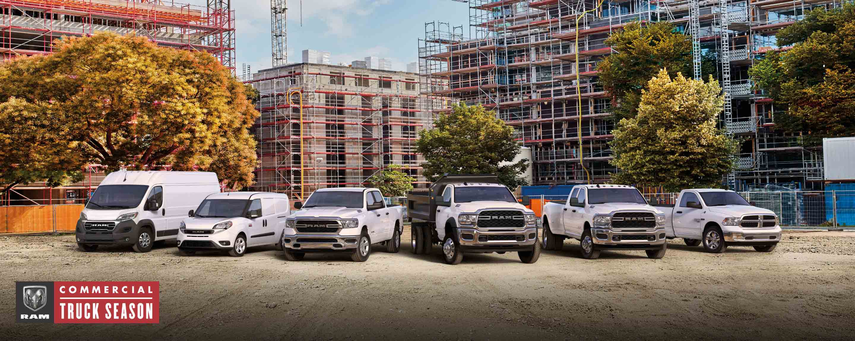 Ram Commercial Truck season. The 2023 Ram lineup parked at a massive commercial construction site. From left to right: a Ram ProMaster High Roof, Ram ProMaster City Cargo Van, Ram 1500, Ram 5500 Chassis Cab with dump body, Ram 3500 and Ram 1500 Classic.