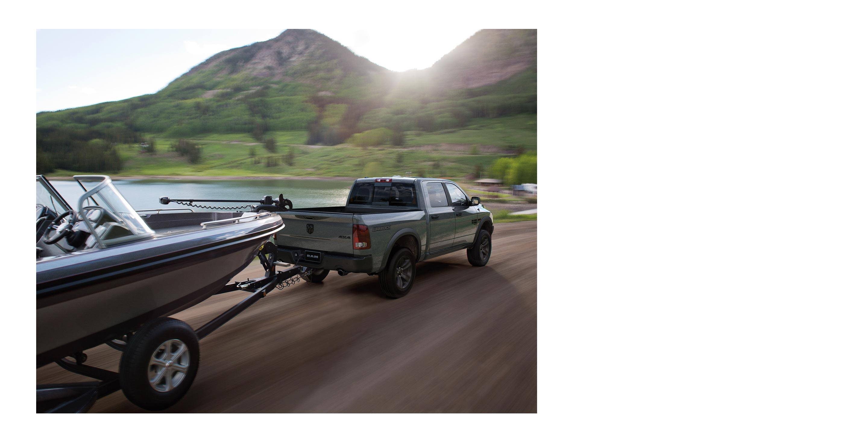 The 2022 Ram 1500 Classic towing a motorboat with the scenery blurred to indicate its speed.