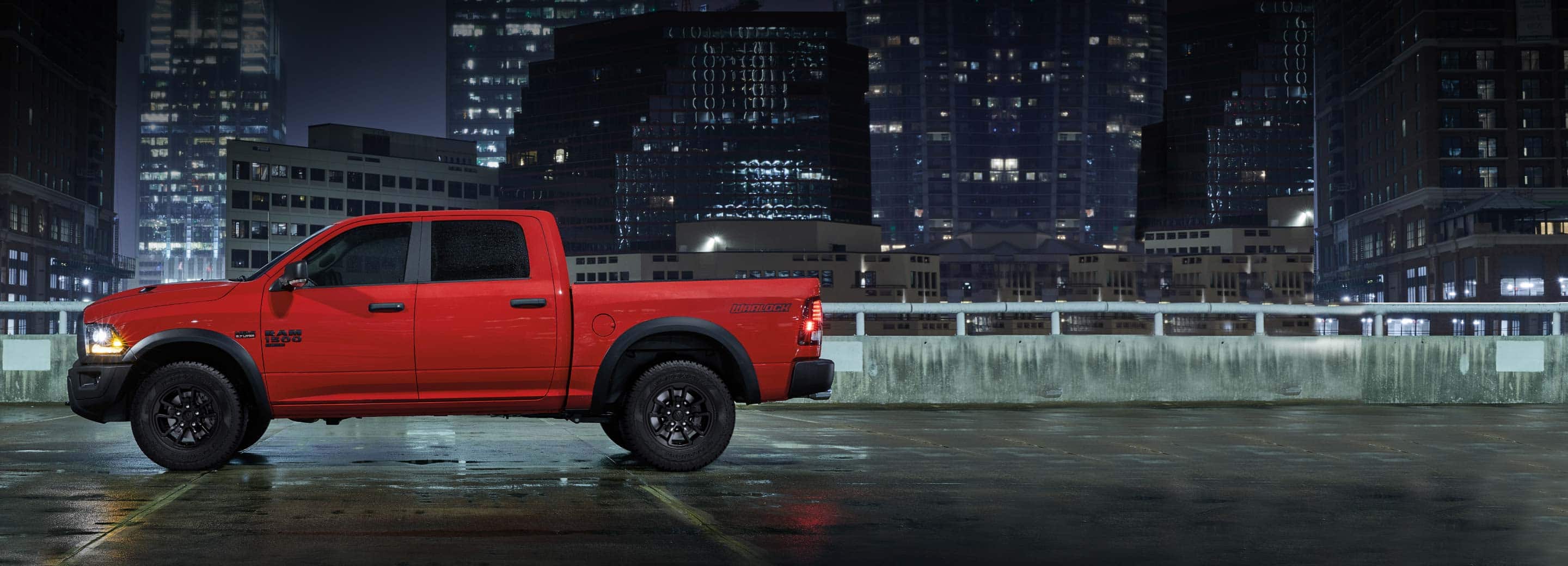 A 2022 Ram 1500 Classic Warlock 4x4 parked on the roof of a parking garage with skyscrapers in the background.