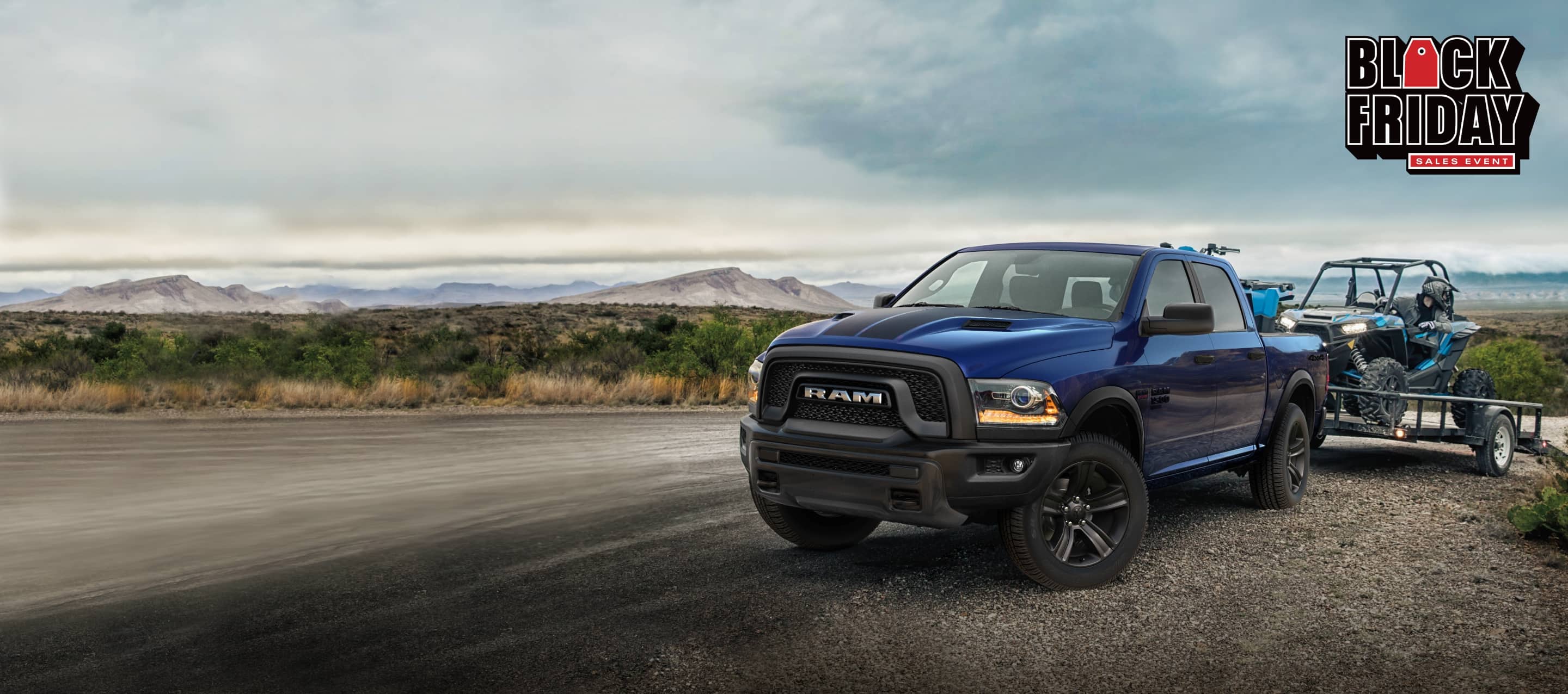 The 2022 Ram 1500 Classic Warlock Crew Cab 4x4 with a flatbed trailer attached, and a driver backing an ATV off the trailer. The Black Friday Sales Event.