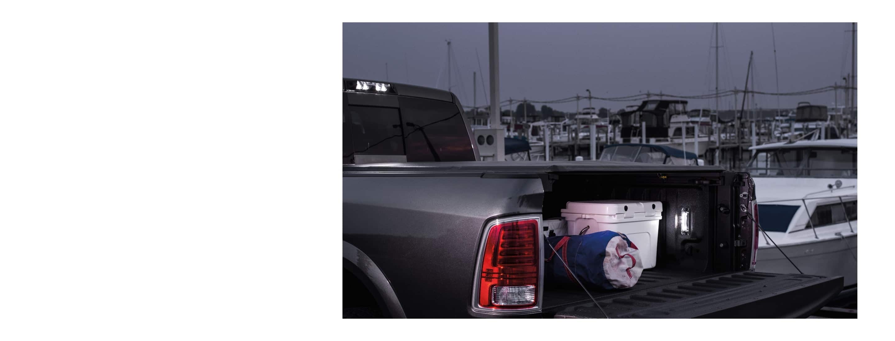 The bed of the 2022 Ram 1500 Classic with the tailgate down to reveal a cooler and duffel bag under the tonneau cover.