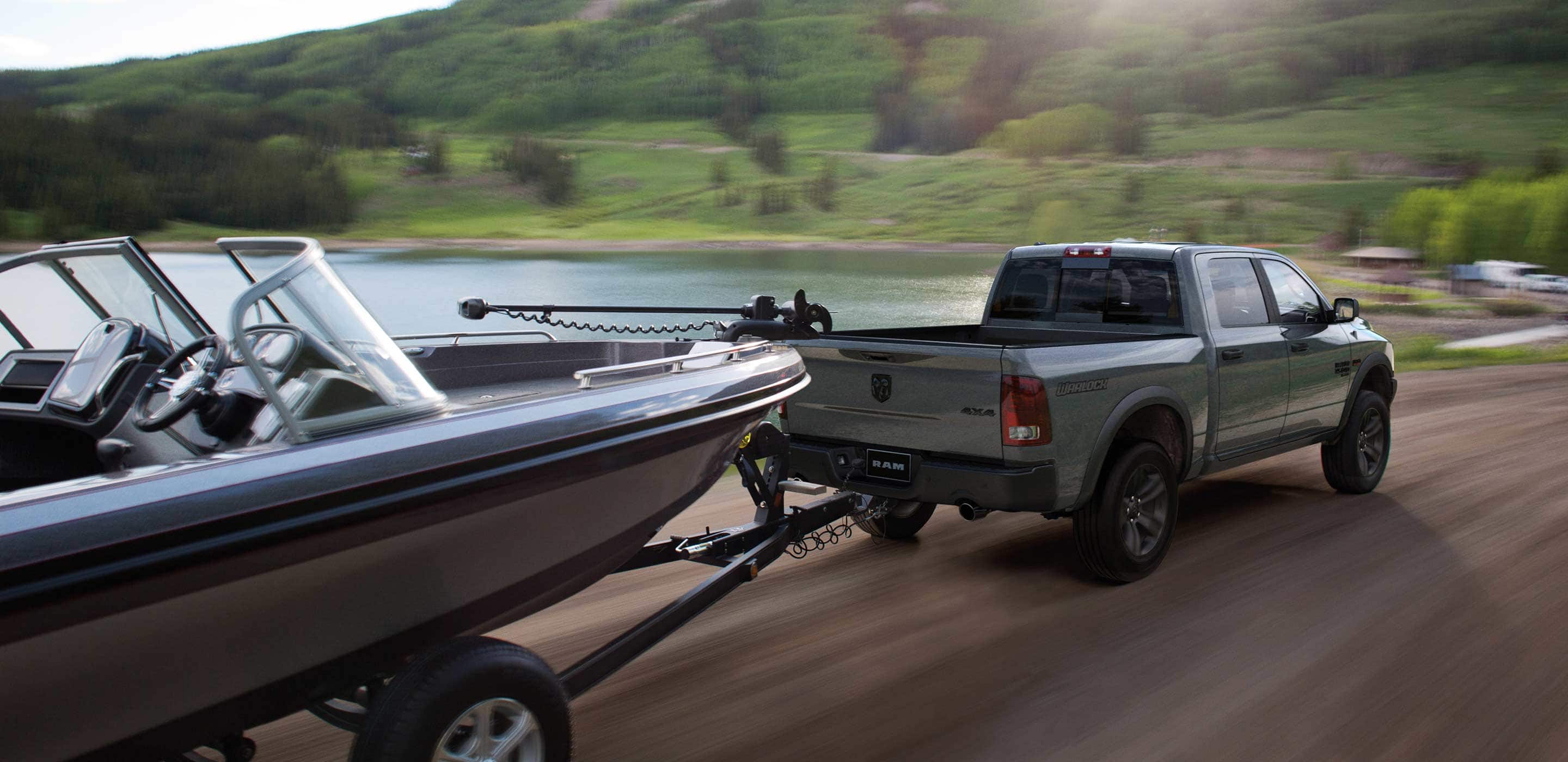 Display The 2022 Ram 1500 Classic towing a motorboat with the scenery blurred to indicate its speed.