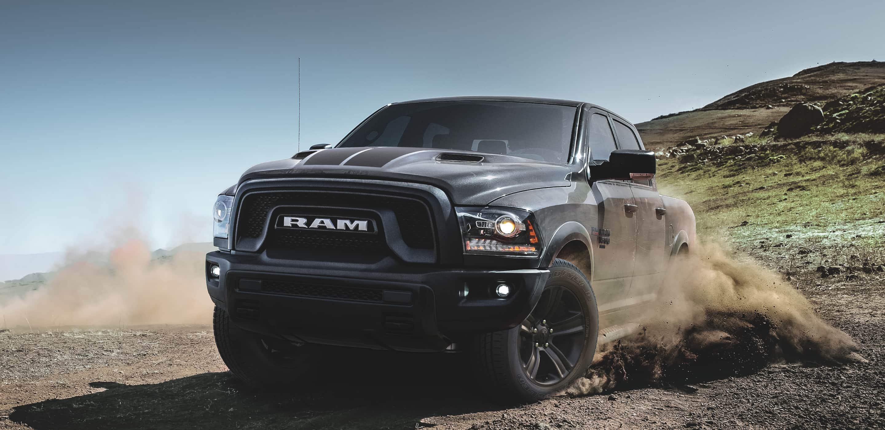 Display The 2022 Ram 1500 Classic throwing up dirt from its wheels as it's driven off-road.