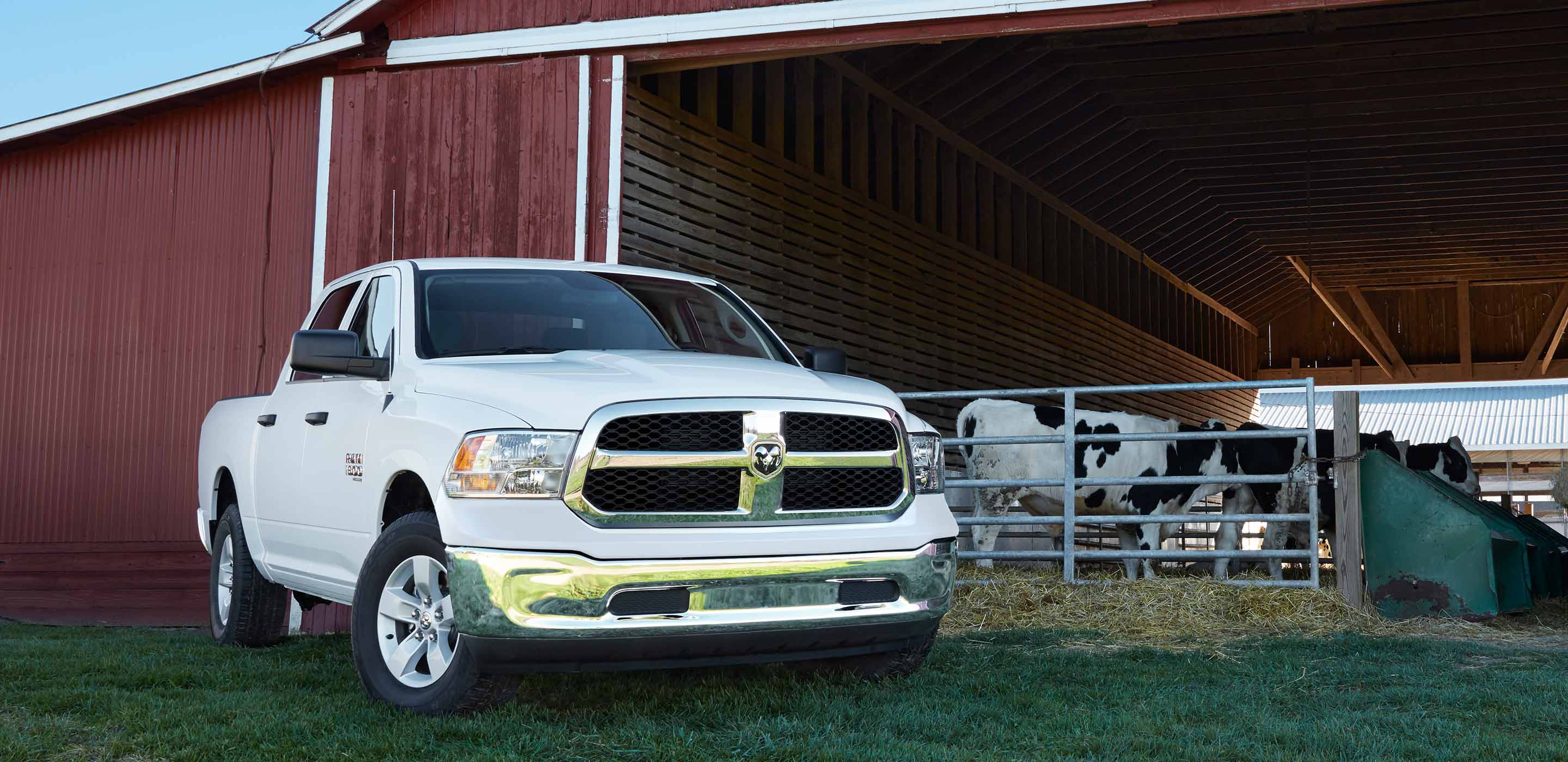 Display The 2022 Ram 1500 Classic parked on the grass outside a cattle barn.