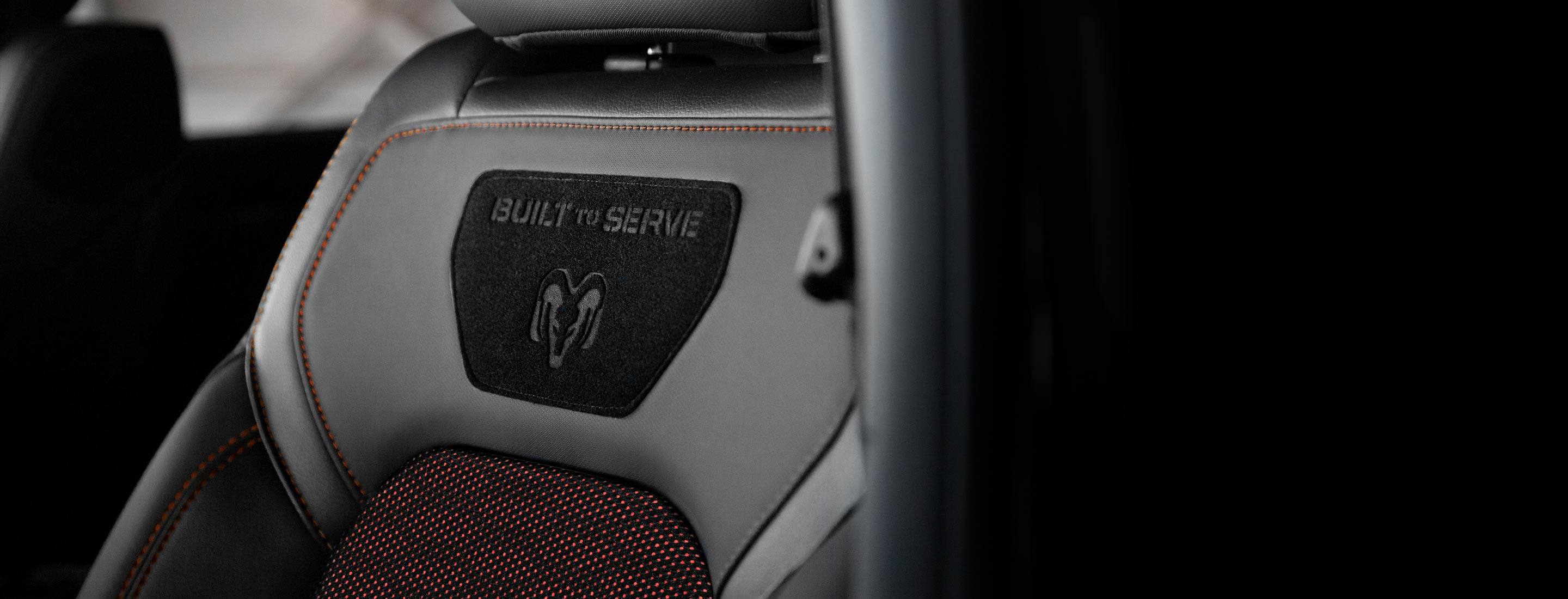 A close-up of the Ram's Head logo and Built to Serve logo on the seatback in the 2022 Ram 1500 Big Horn Built to Serve Edition.