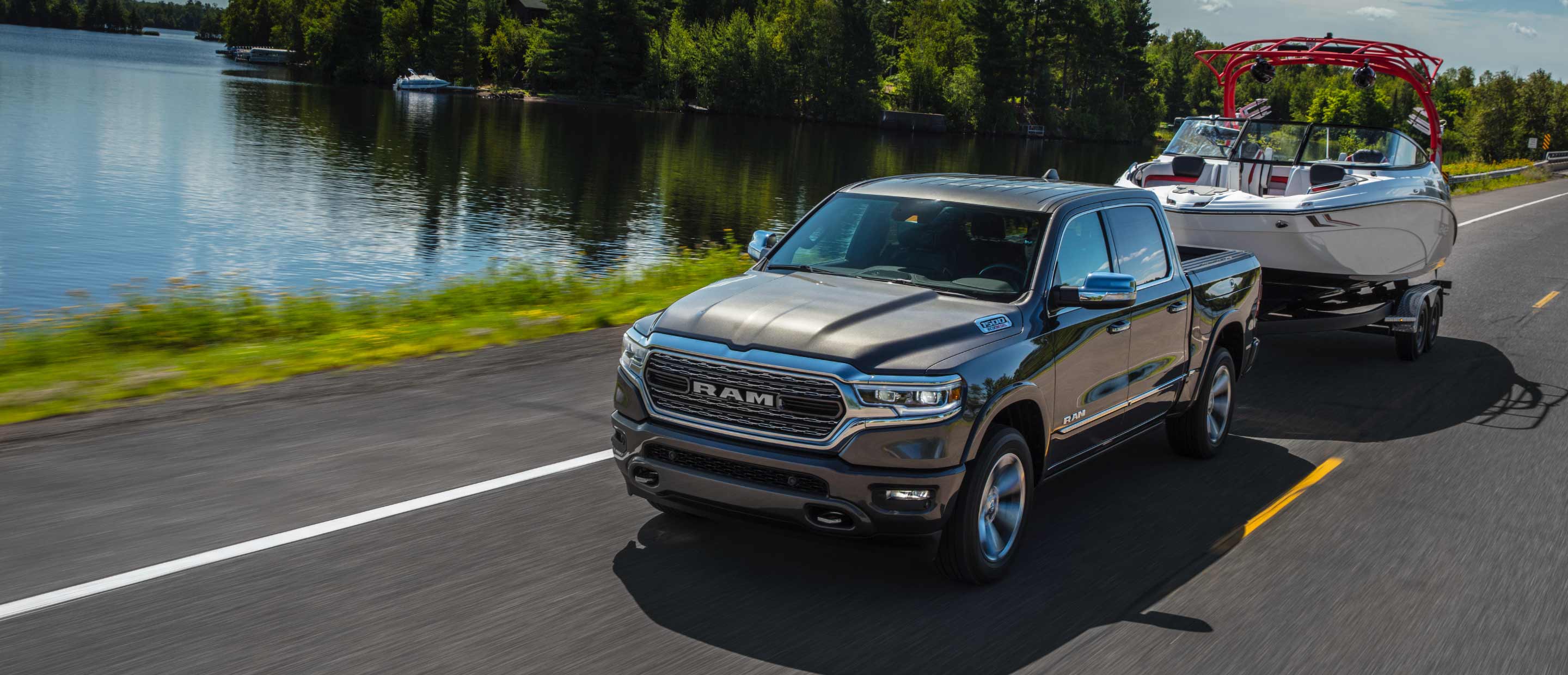 The 2022 Ram 1500 towing a boat beside a lake.