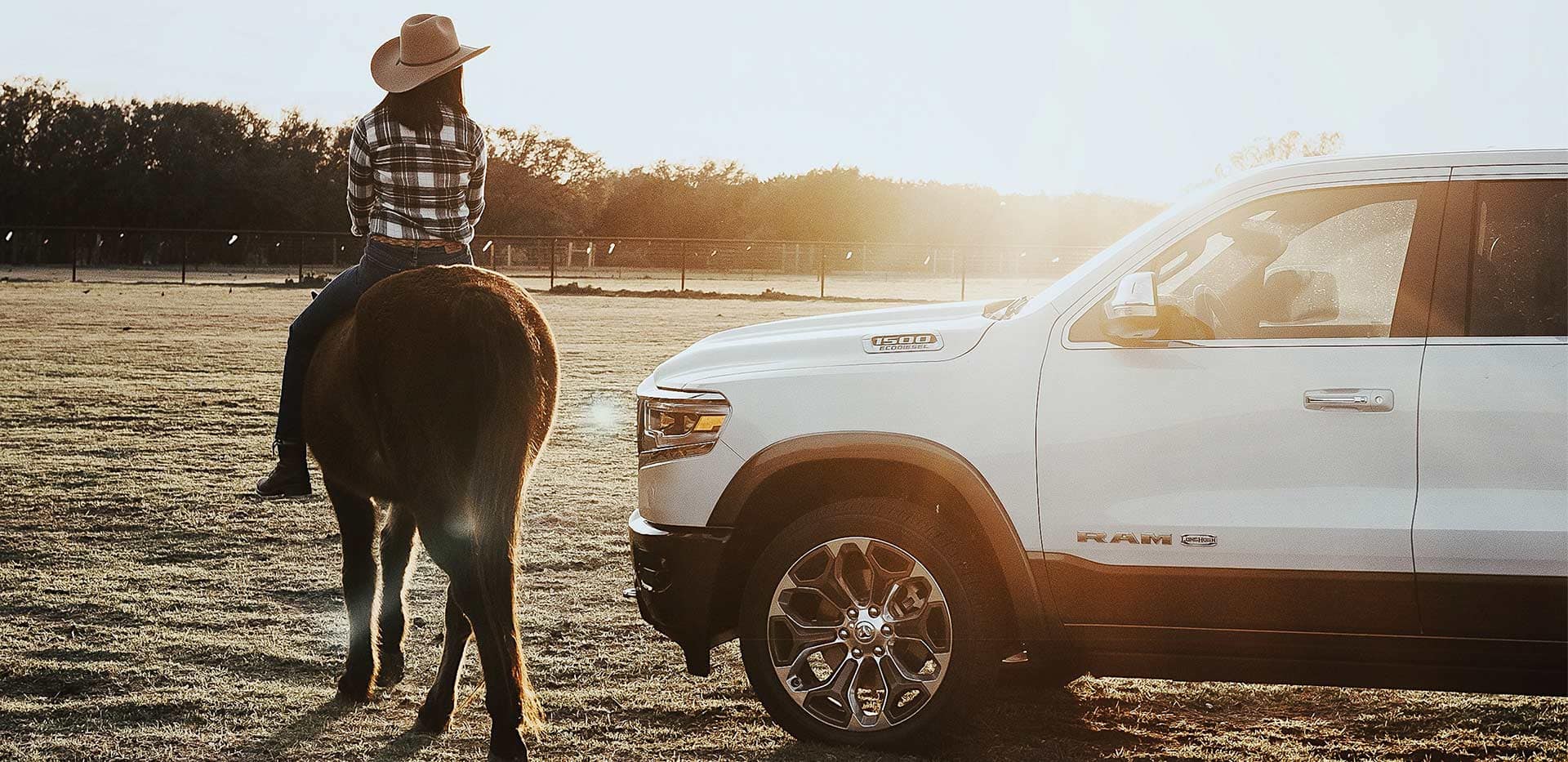 Display A 2022 Ram 1500 parked in a paddock with a woman on a horse beside it.