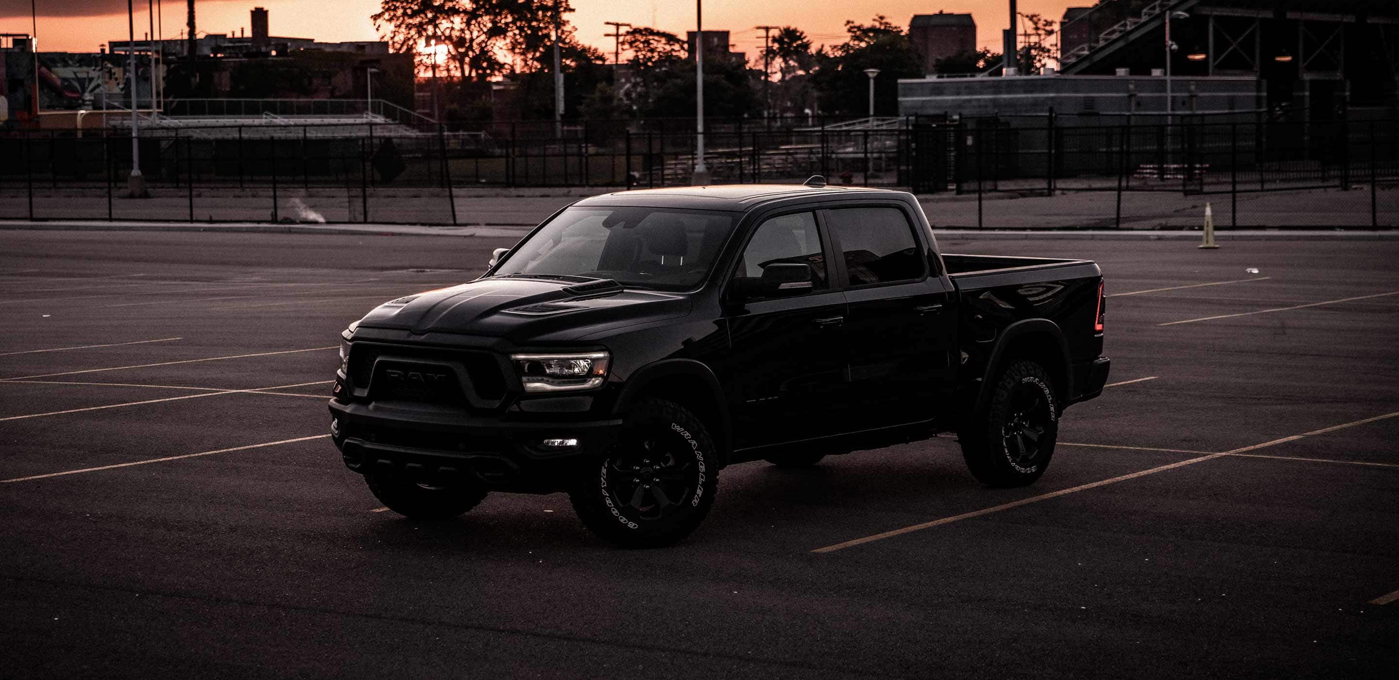 Display The 2022 Ram 1500 in a parking lot outside a sports field at dusk.