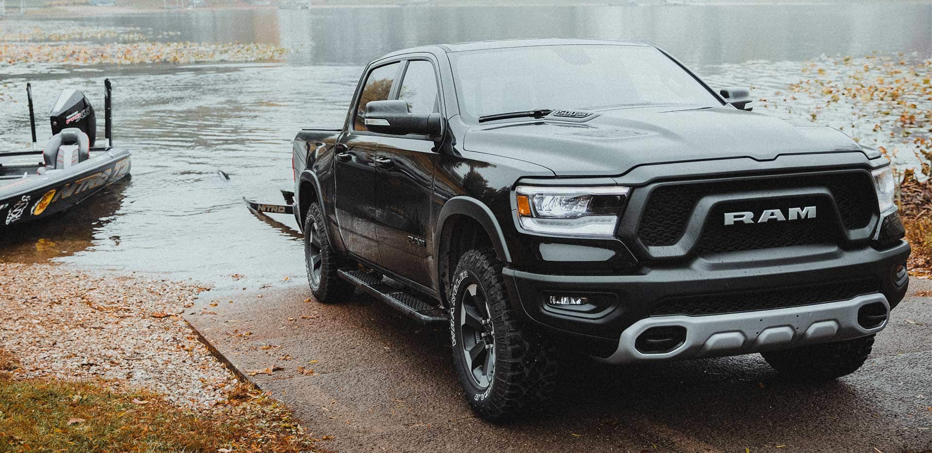 Display The 2022 Ram 1500 with a boat trailer parked at the edge of a lake.