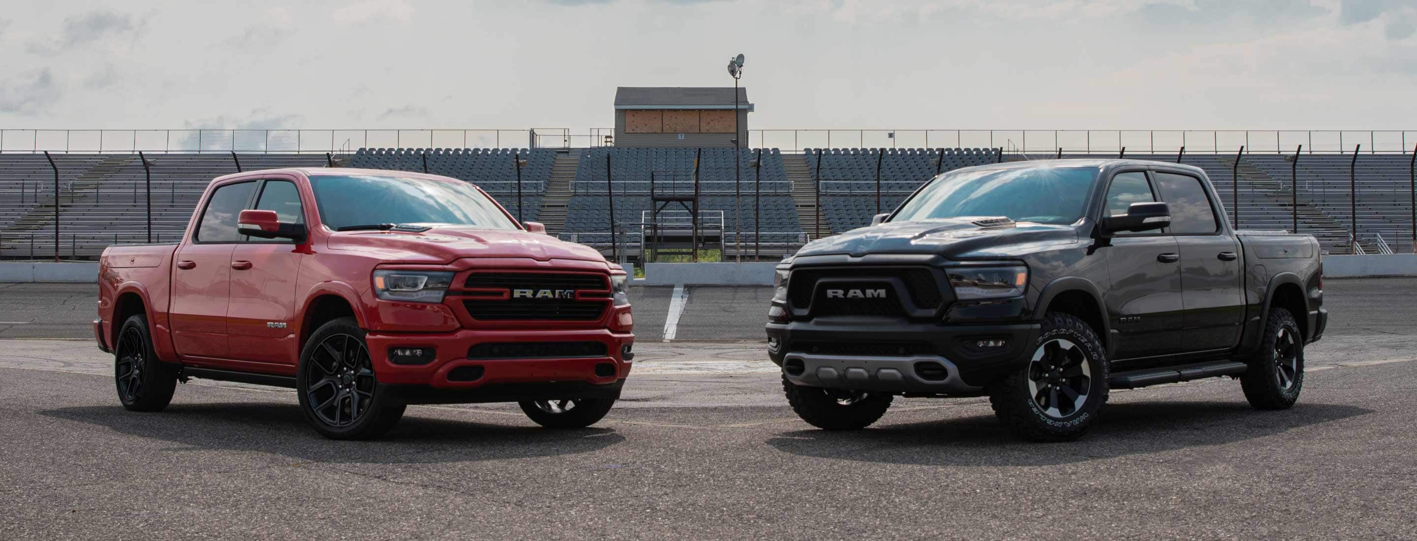 The 2022 Ram 1500 Laramie G/T and Rebel G/T parked on a racetrack in front of the bleachers.