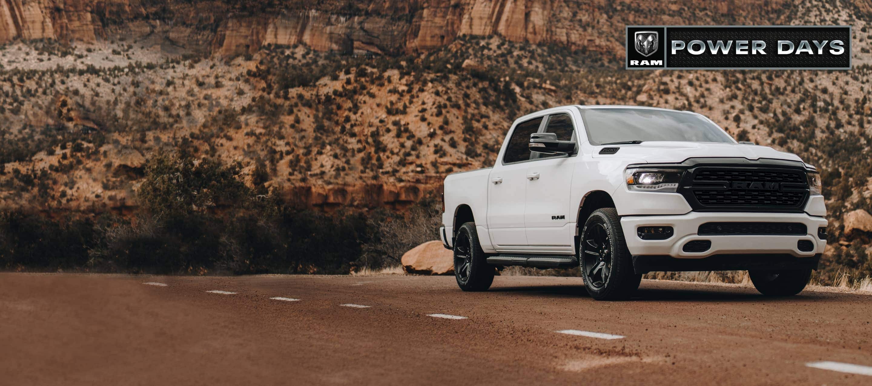A white 2022 Ram 1500 Big Horn Crew Cab being driven on a mountain road. Ram Power Days.