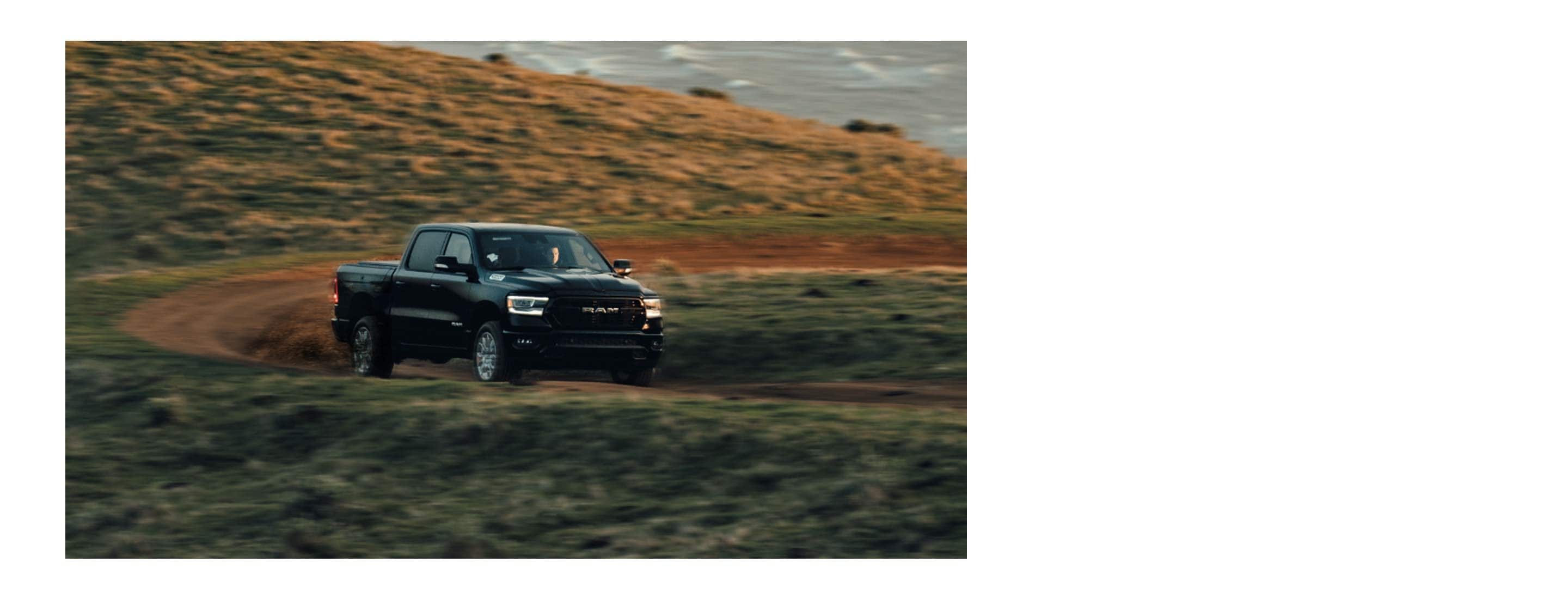 The 2022 Ram 1500 being driven on a winding dirt road.