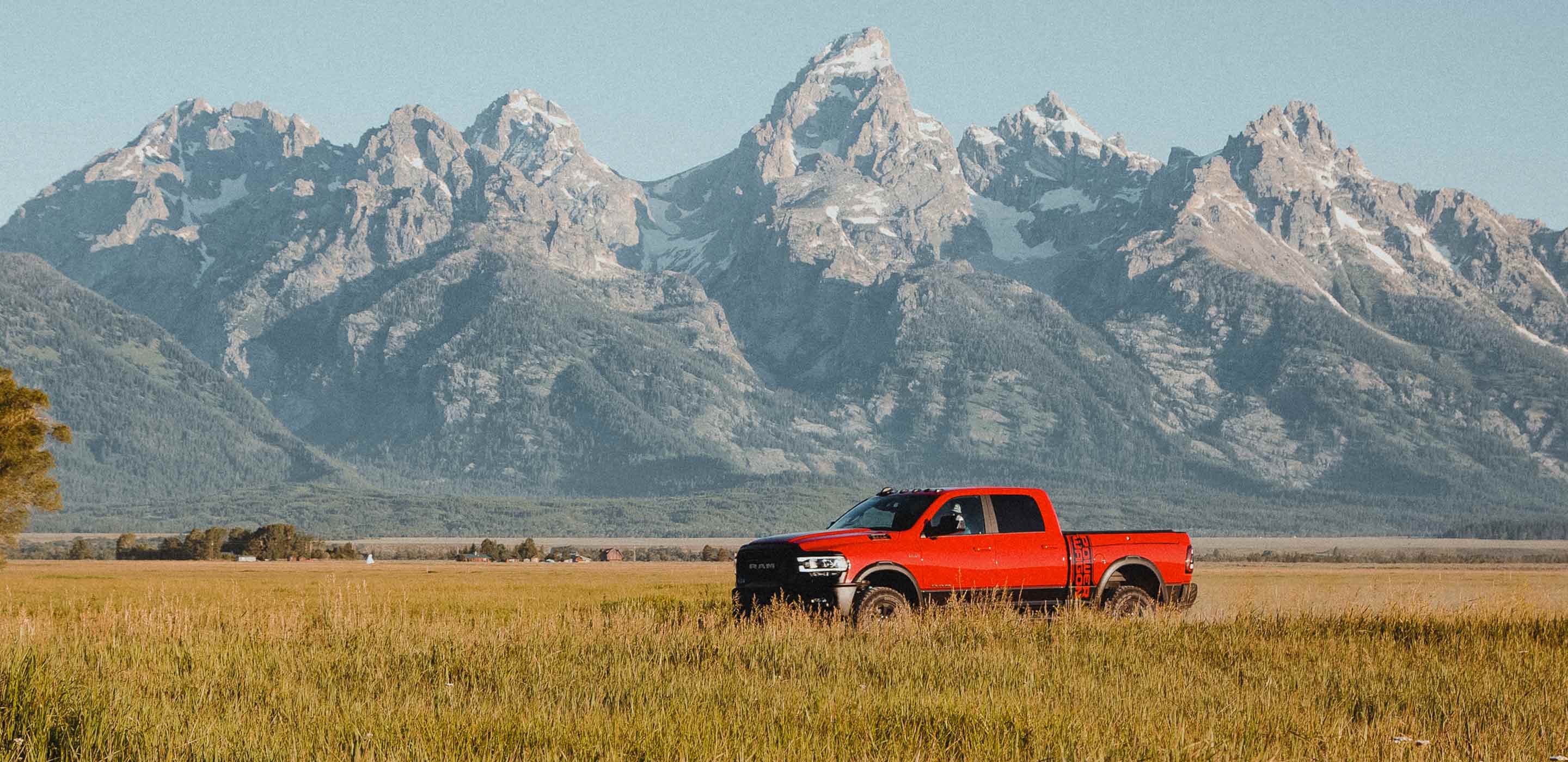 Display The 2022 Ram 2500 parked in tall grass in front of a mountain backdrop.