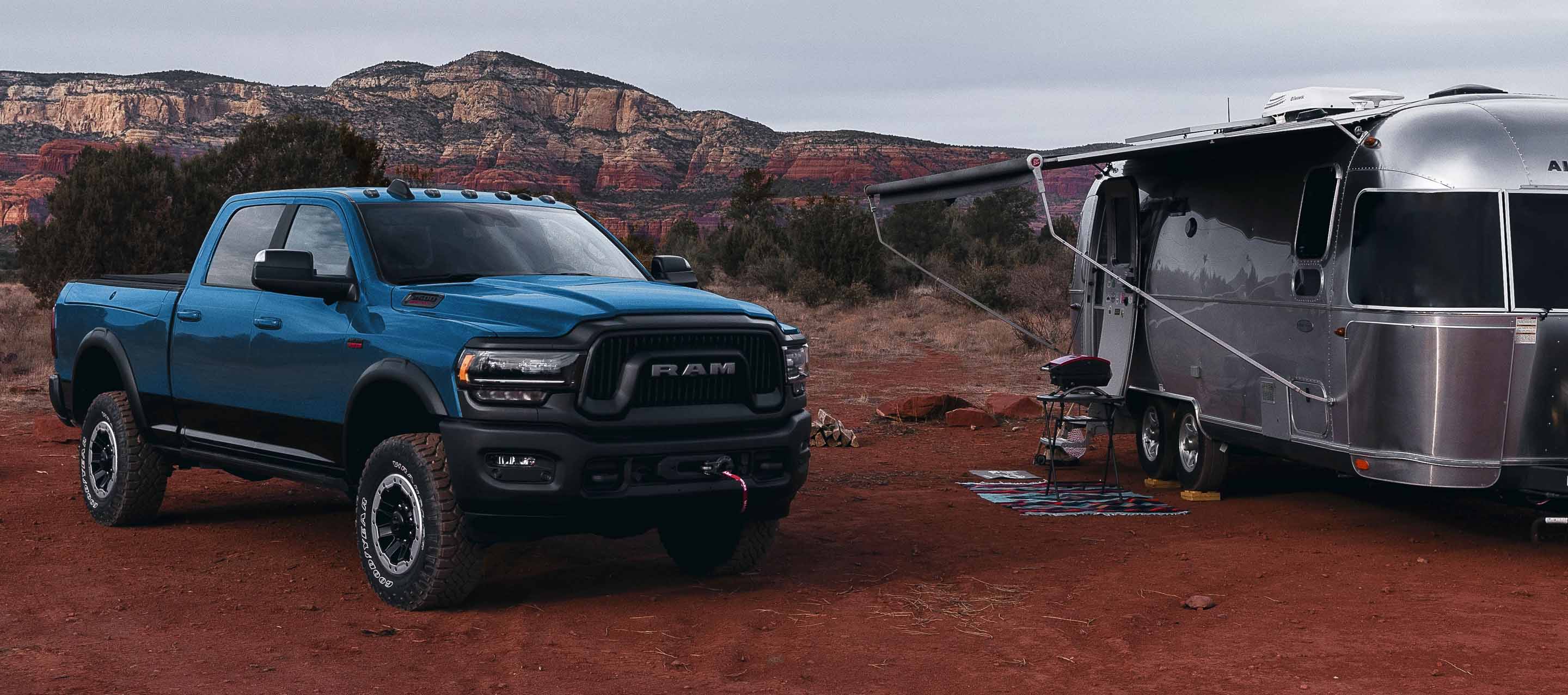 The 2022 Ram 2500 parked in the desert beside a camper.