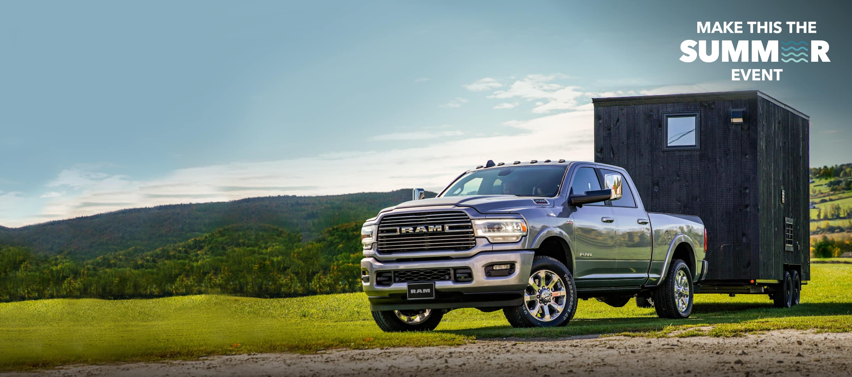 A 2022 Ram 2500 Laramie Crew Cab towing a small trailer down a country road. Make This The Summer Event.