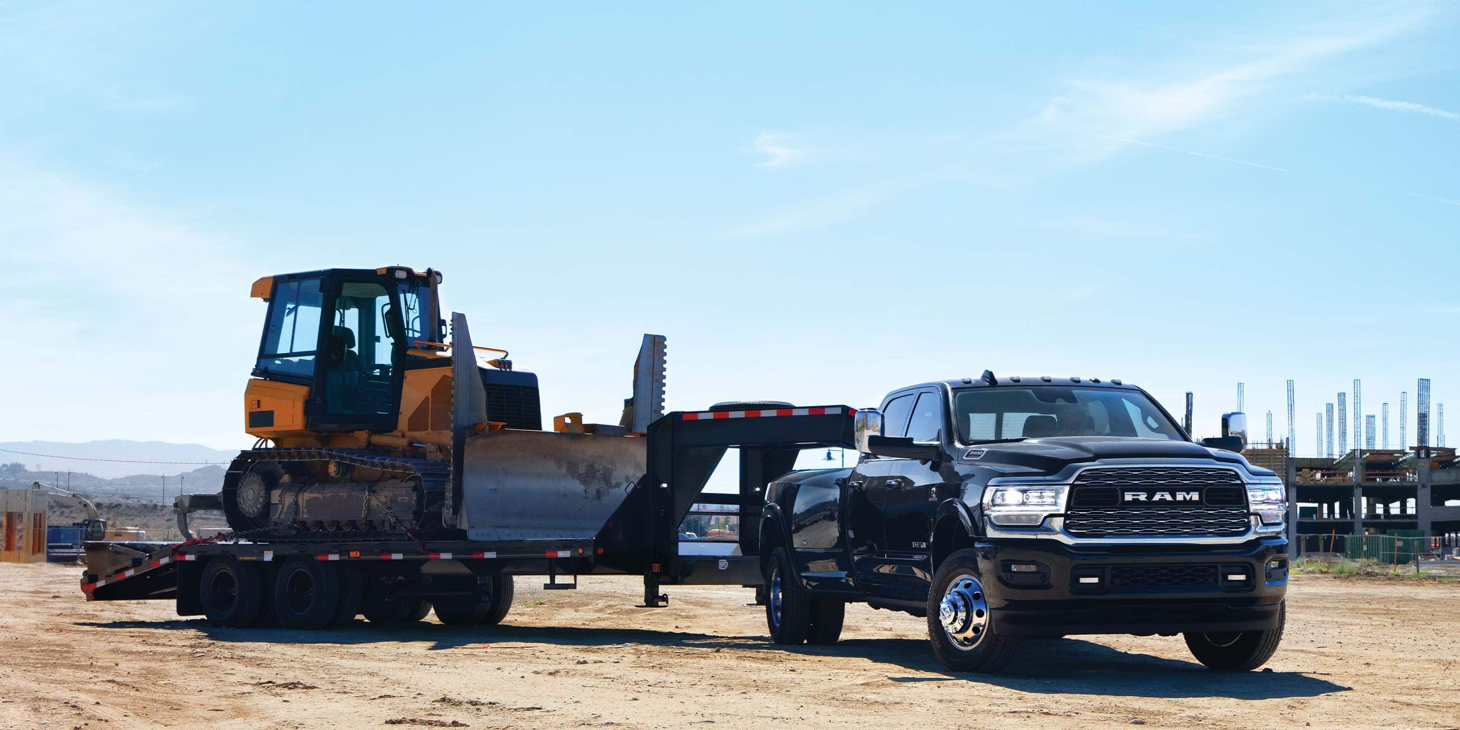 The 2022 Ram 3500 Limited towing an excavator on a flatbed with a fifth-wheel hitch.