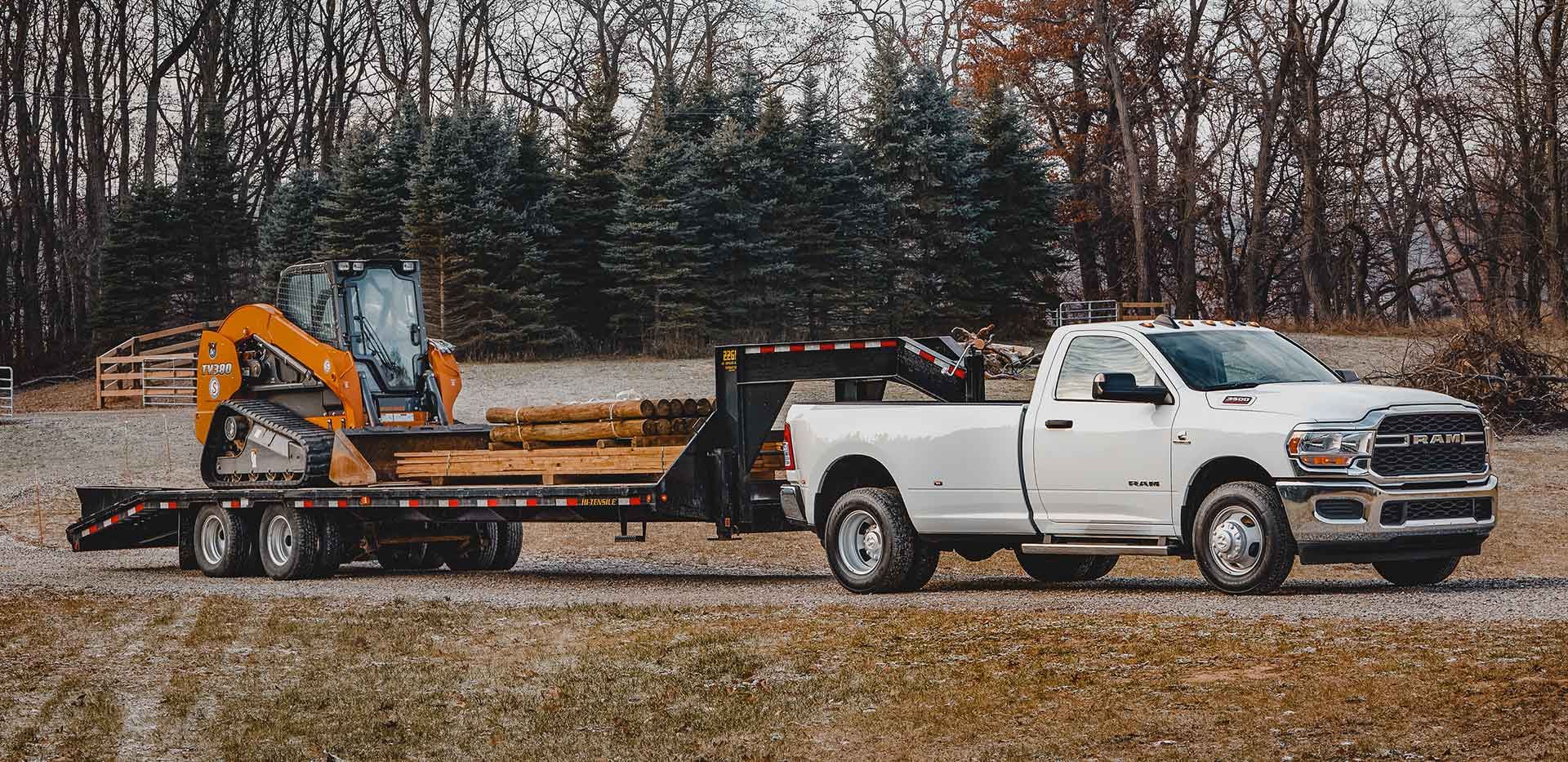 Display The 2022 Ram 3500 towing a flatbed loaded with an excavator.