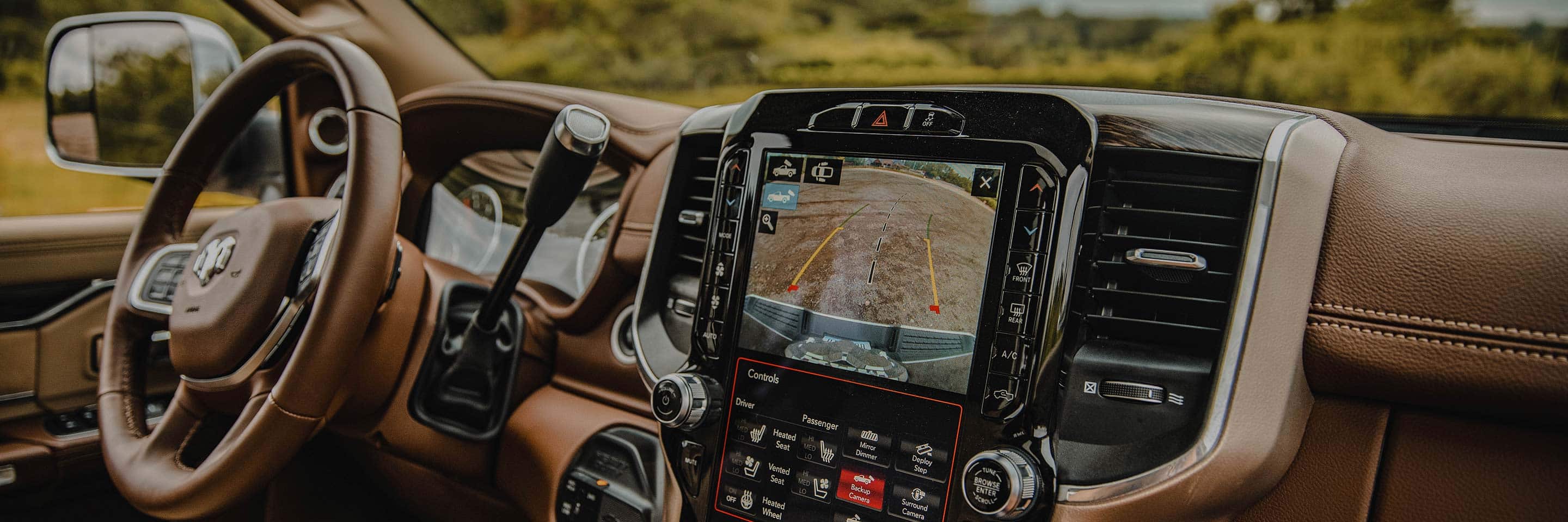 The interior of the 2022 Ram 3500 showing the steering wheel and touchscreen, which is displaying the area behind the vehicle.