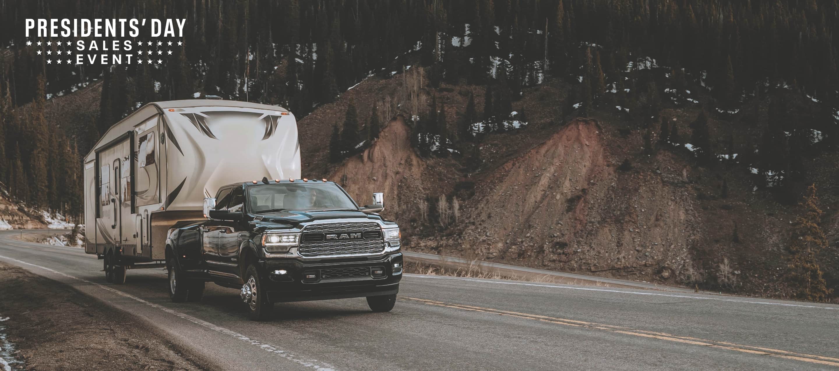 A 2022 Ram 3500 Limited 4x4 Crew Cab towing a fifth wheel travel trailer as it travels down a mountain road. The Presidents' Day Sales Event logo.