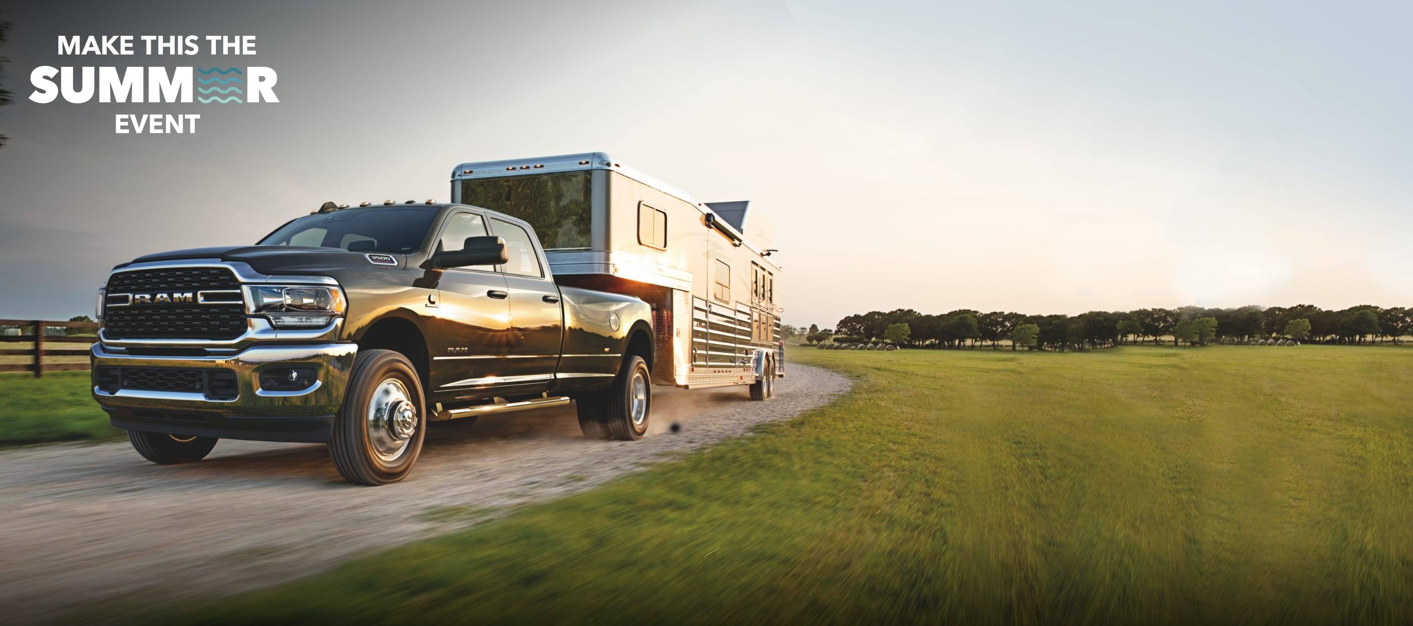 The 2022 Ram 3500 pulling a horse trailer on a gravel road. Make This the Summer Sales Event logo.