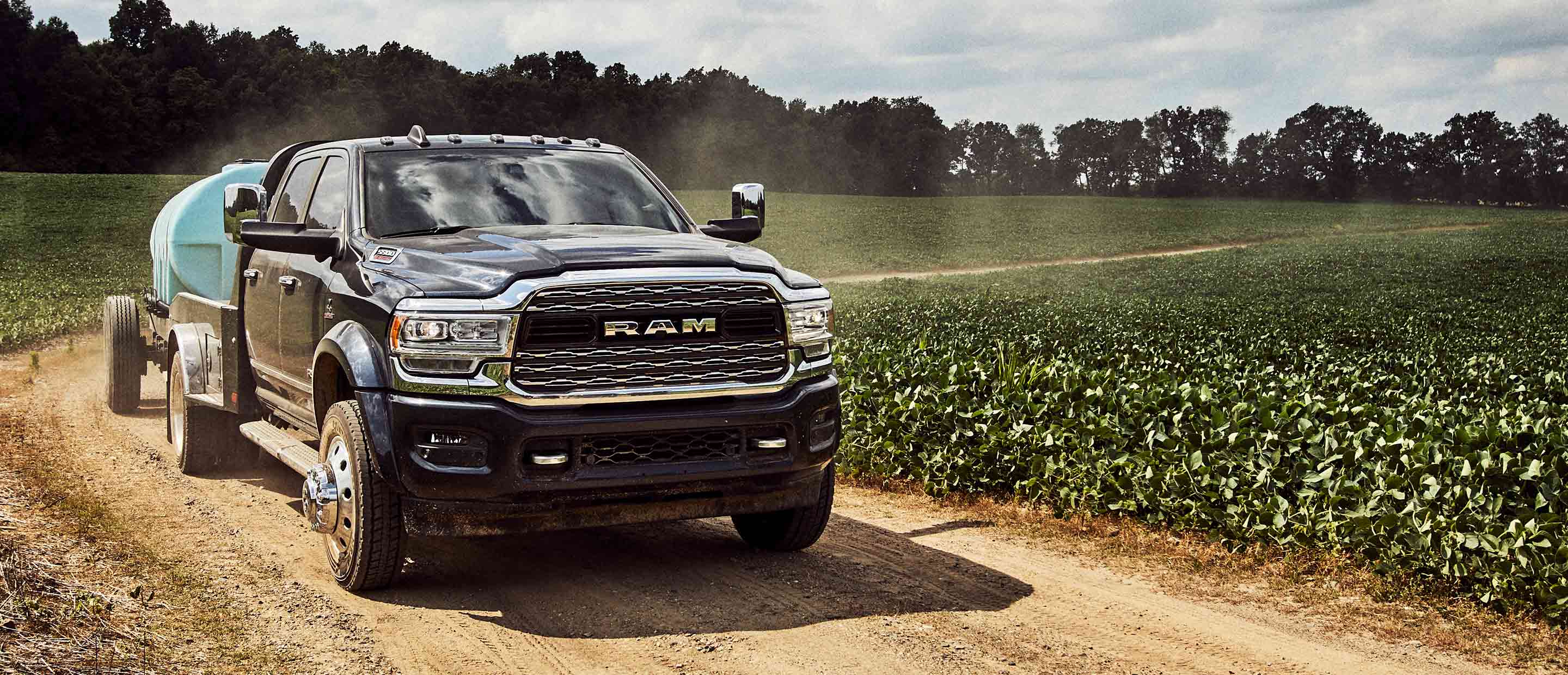 The 2022 Ram Chassis Cab carrying an irrigation tank, being driven on a dirt road.