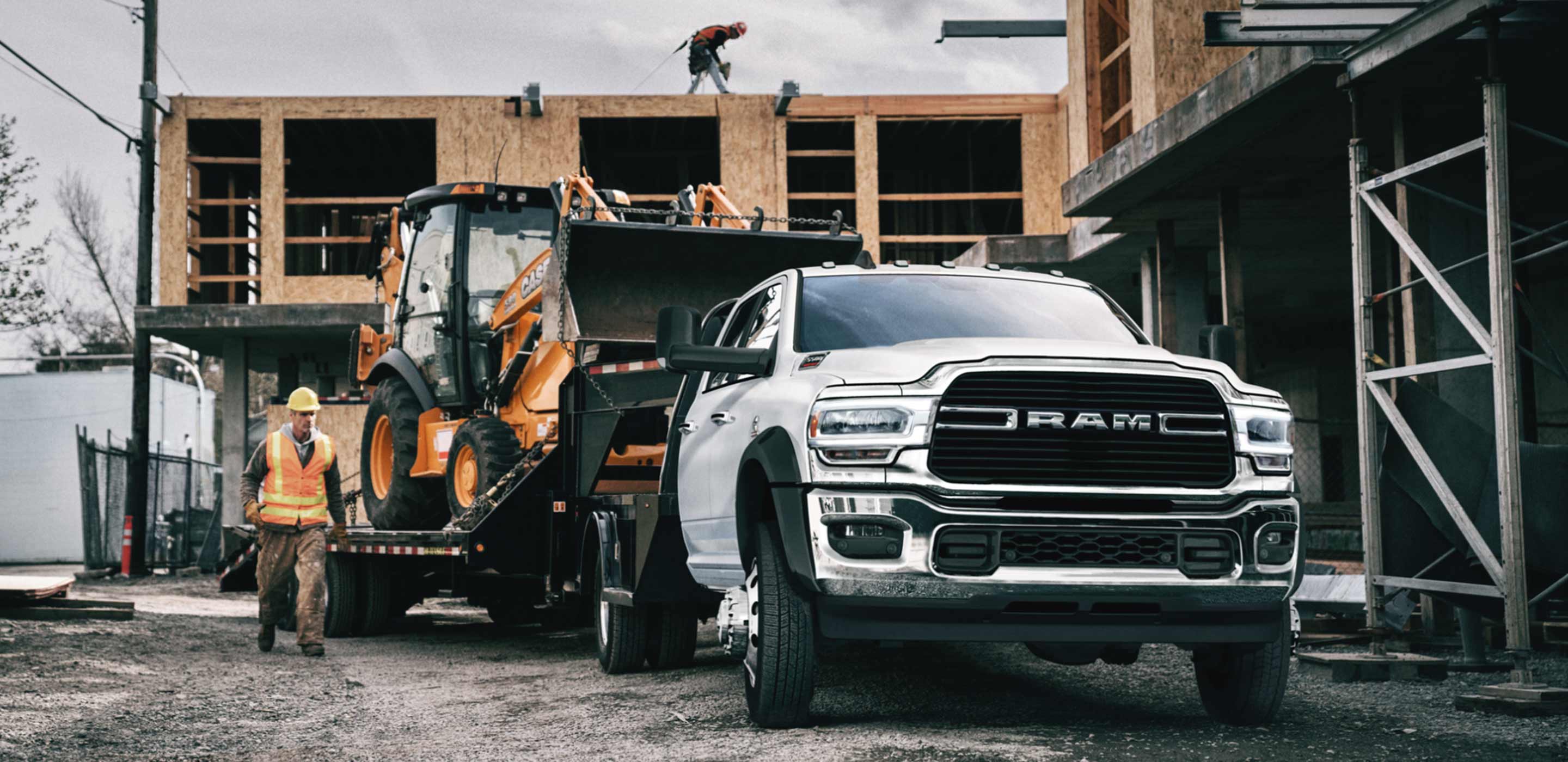 Display The 2022 Ram Chassis Cab on a construction site with an excavator in tow.