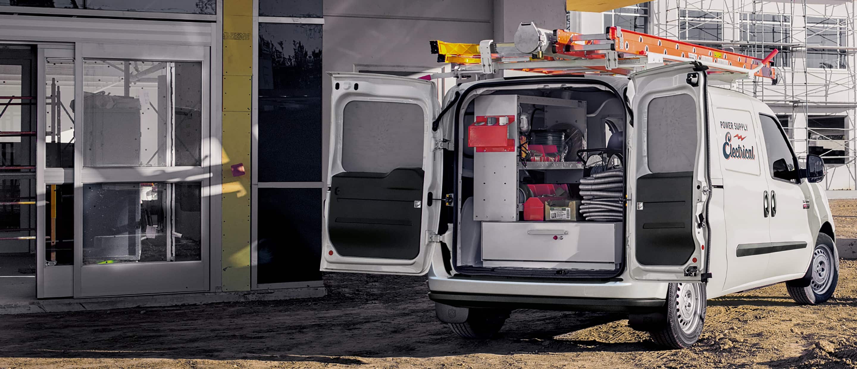 The 2022 Ram ProMaster City with its rear doors open to reveal shelving along one wall and a storage drawer on the floor of the vehicle.