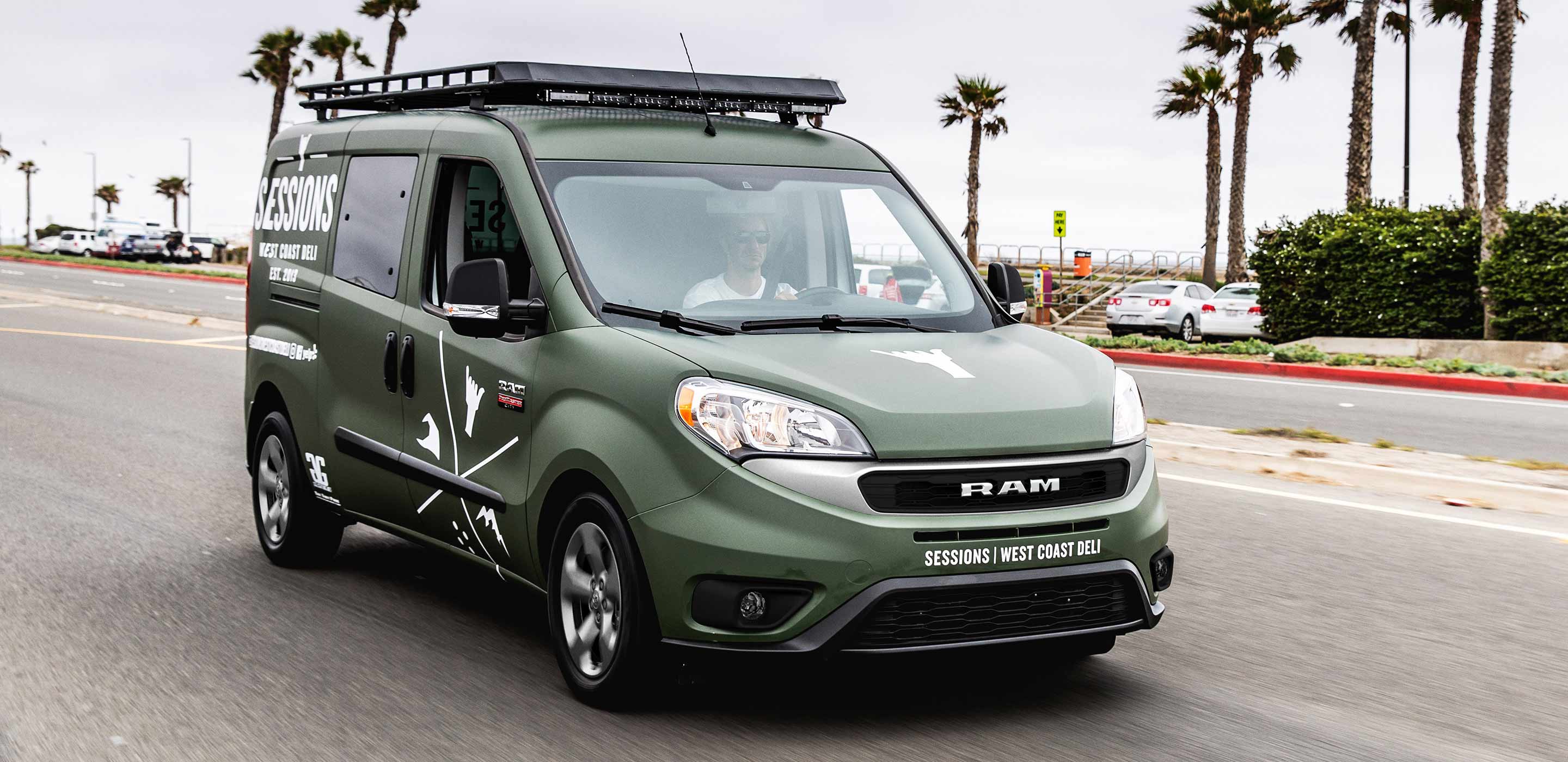 Display The 2022 Ram ProMaster City with an available roof rack and decals for a delicatessen on its front and sides.