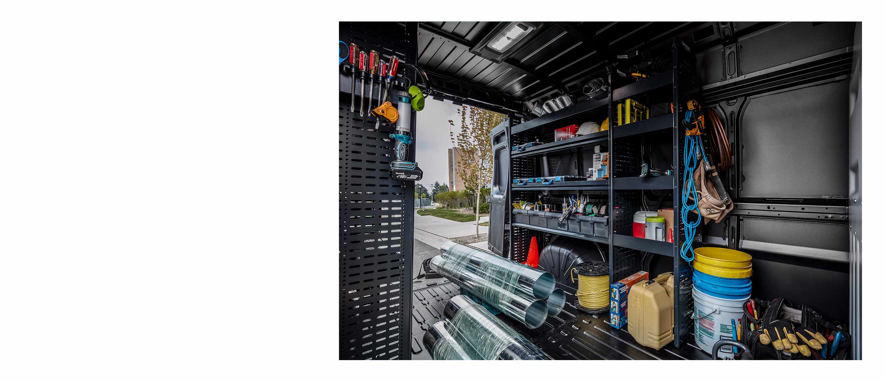 The interior of a 2022 Ram ProMaster with shelves along the van walls and tubes of aluminum flashing on the floor.