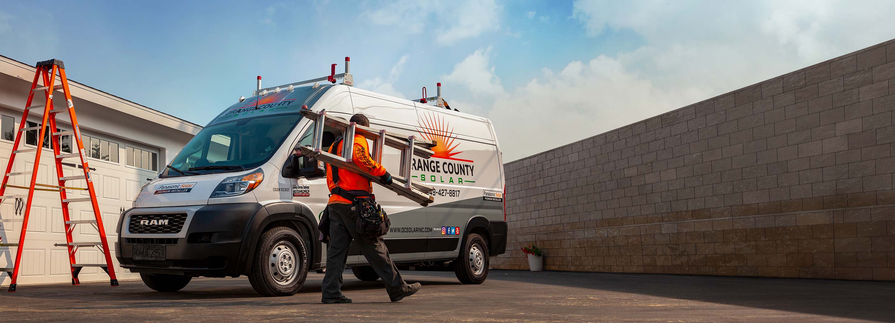 A man carrying a ladder approaches a 2022 Ram ProMaster bearing the logo of a solar company on its side.