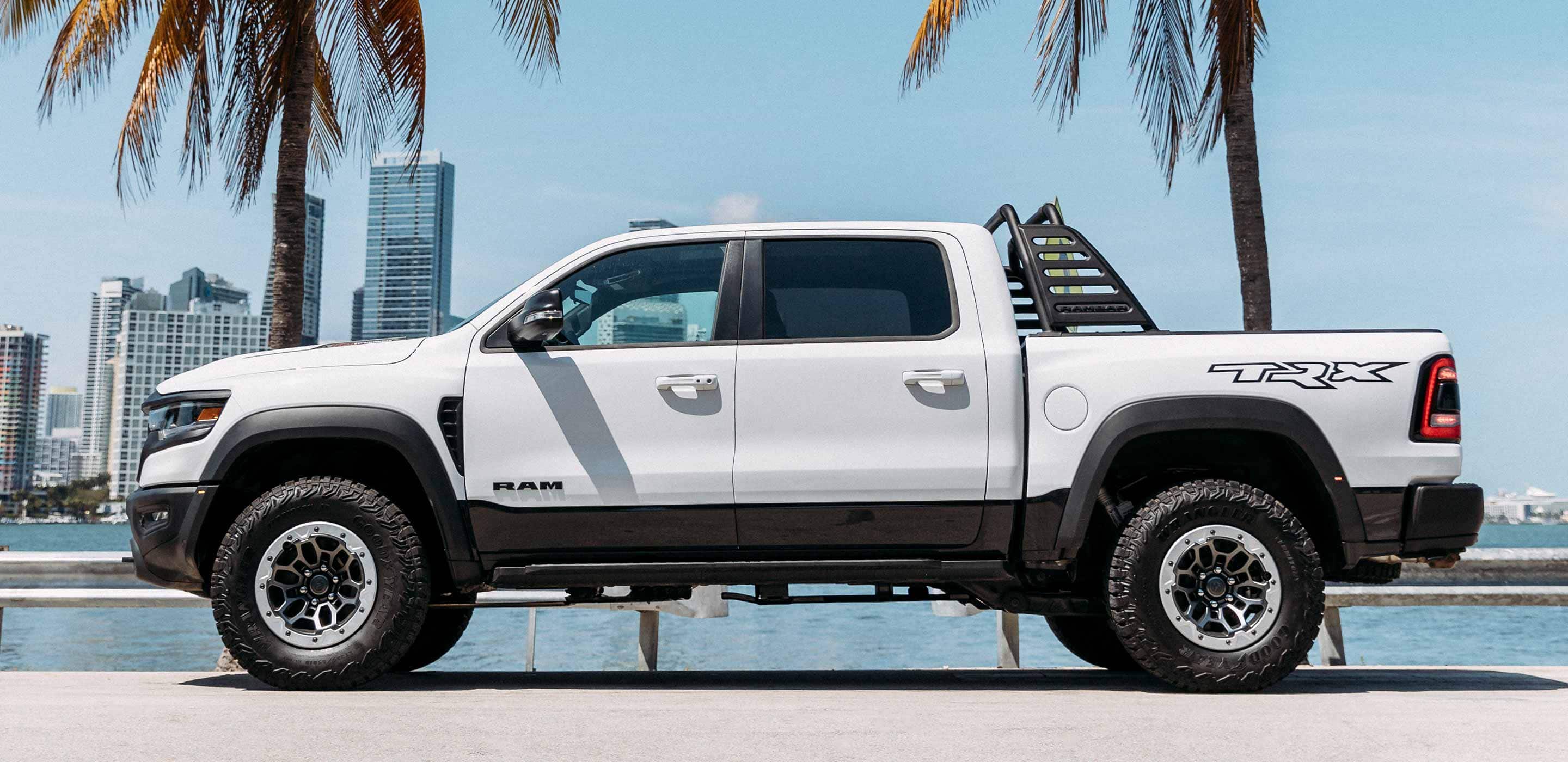 Display The 2022 Ram TRX with available Ram Bar parked by the water with a city skyline in the background.