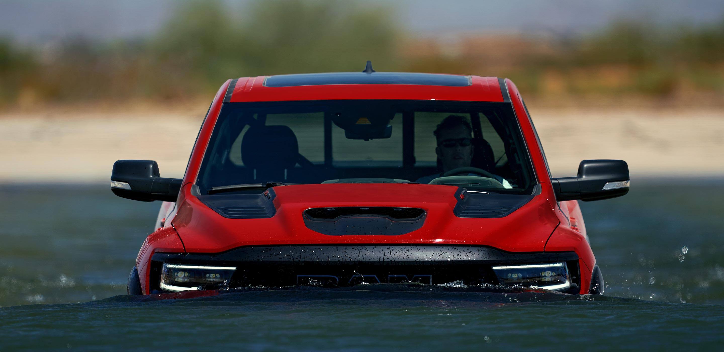 Display The 2022 Ram TRX fording through water that is near the top of the RAM lettering on the grille.