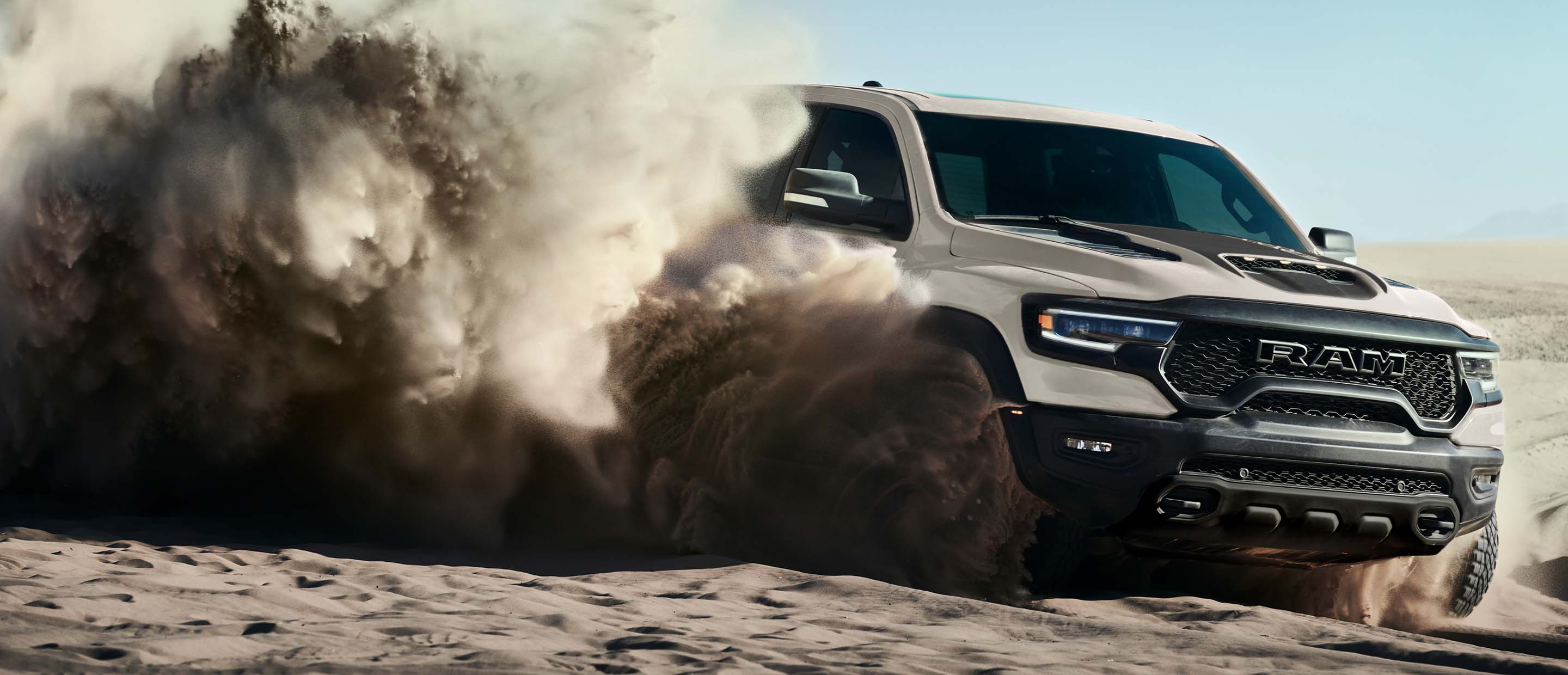 The 2022 Ram 1500 TRX Sandblast Edition being driven on sand with billowing sand clouds obscuring its wheels.