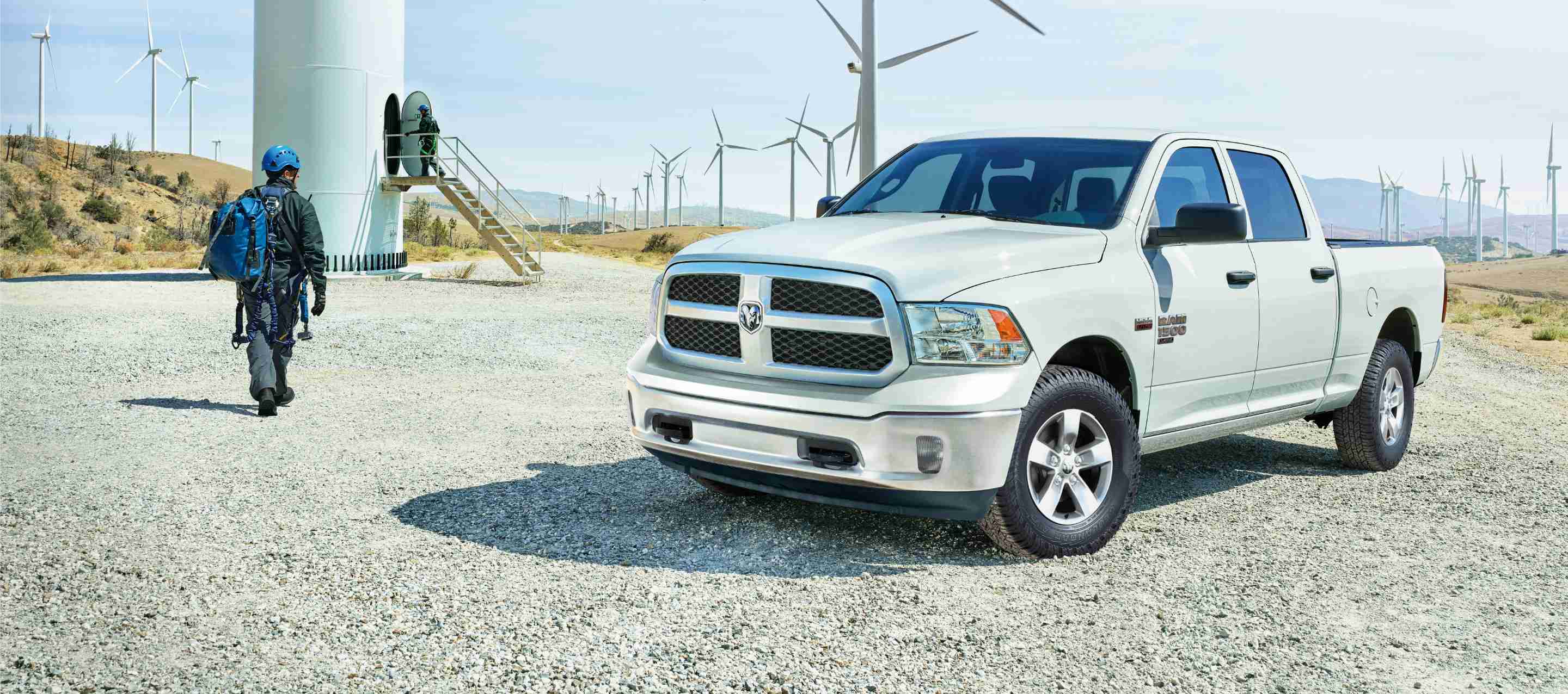 A white 2023 Ram 1500 Classic Tradesman Crew Cab parked beside a field of windmills.
