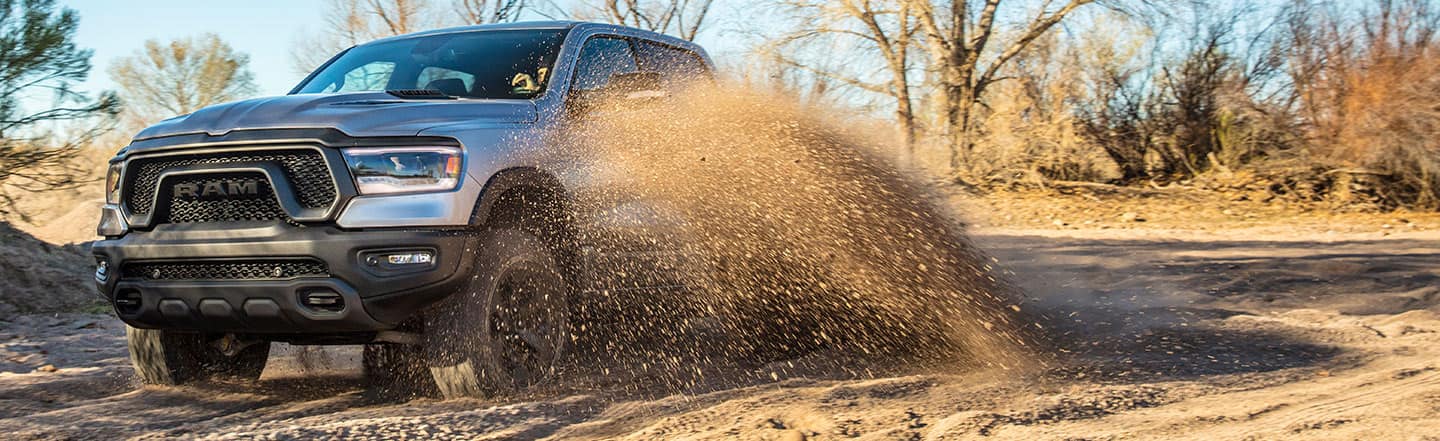 The 2023 Ram 1500 Rebel being driven off-road with dirt spraying up from its wheels.