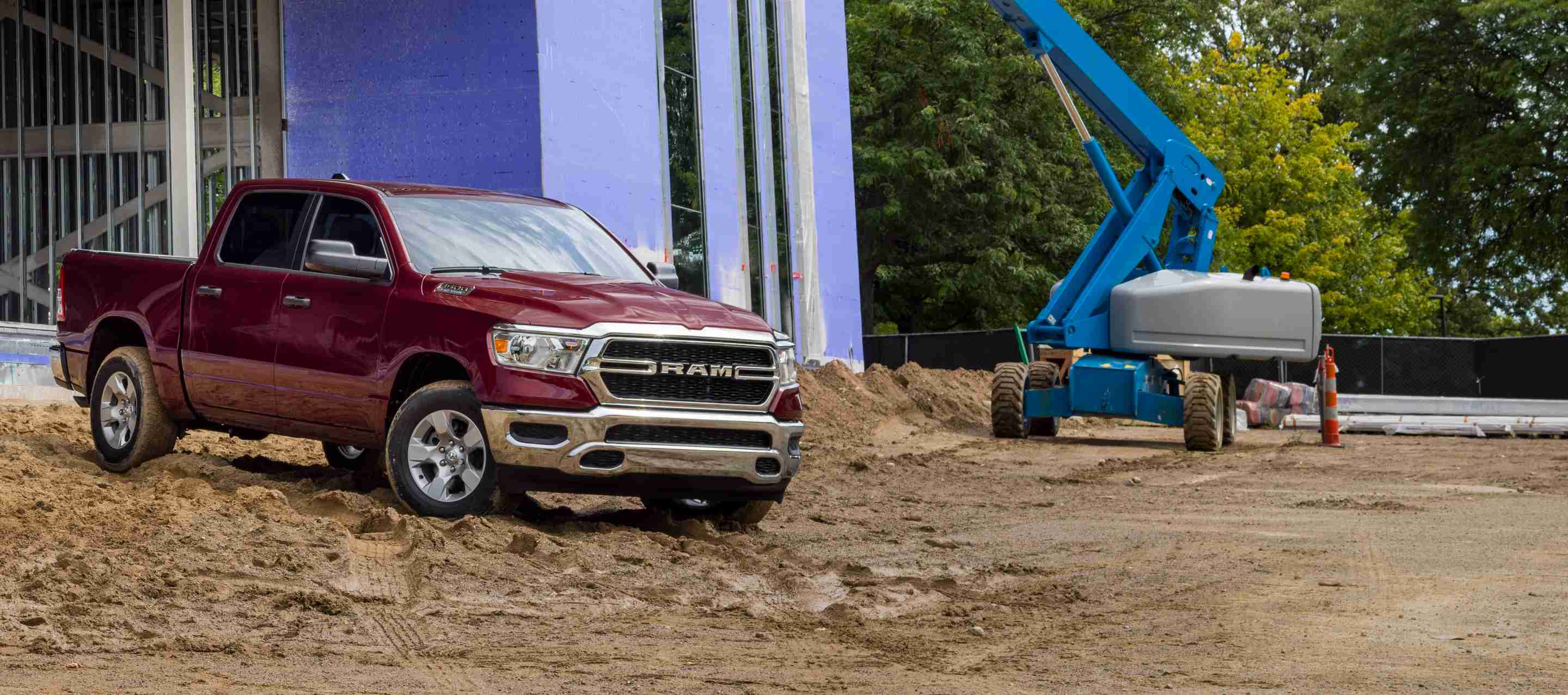 A red 2023 Ram 1500 Tradesman 4x4 Crew Cab parked at a commercial building site.