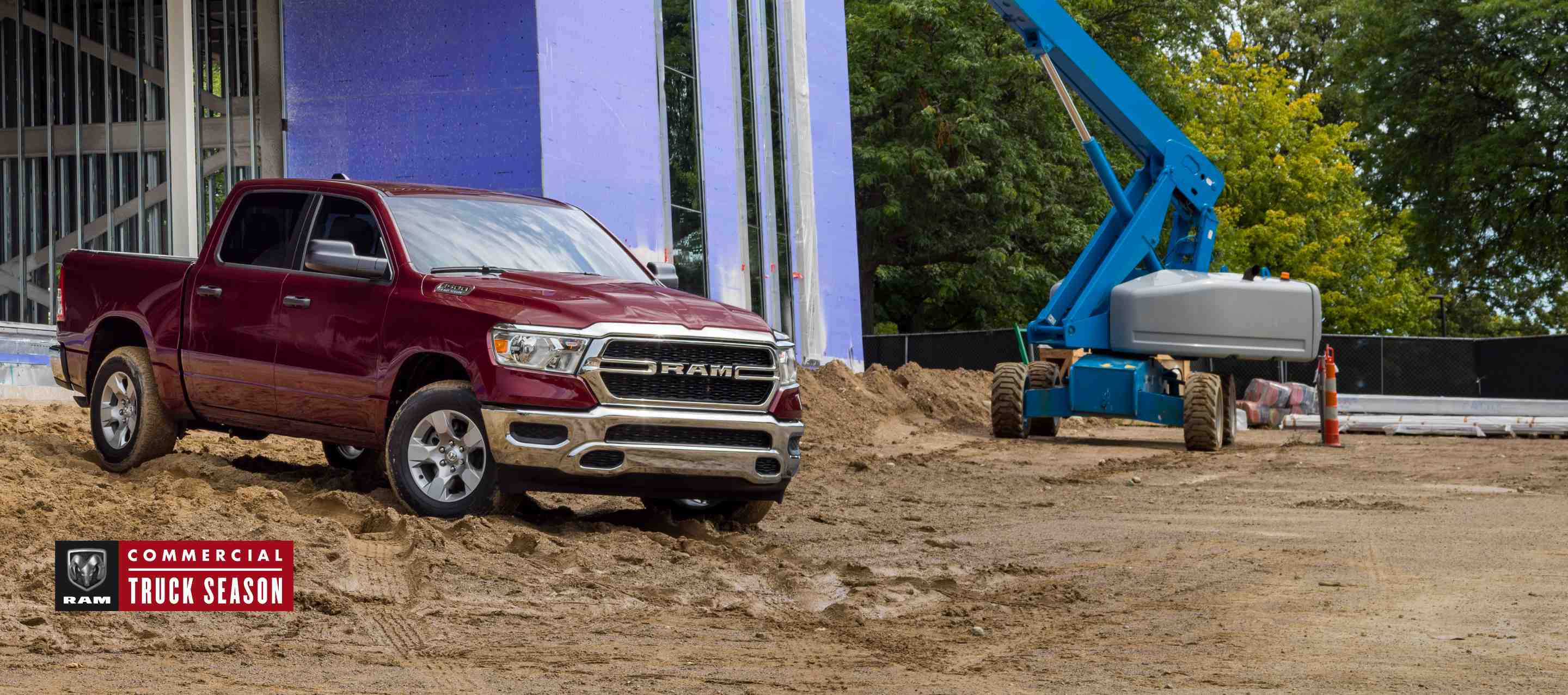 A red 2023 Ram 1500 Tradesman 4x4 Crew Cab parked at a commercial building site. Ram Commercial Truck Season.