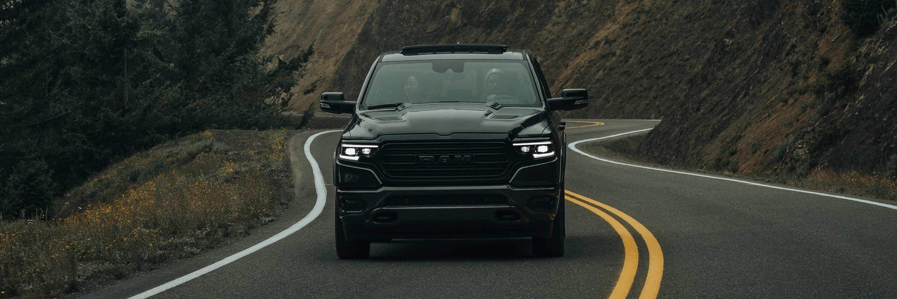 A head-on view of the 2023 Ram 1500 being driven on a winding mountain road.