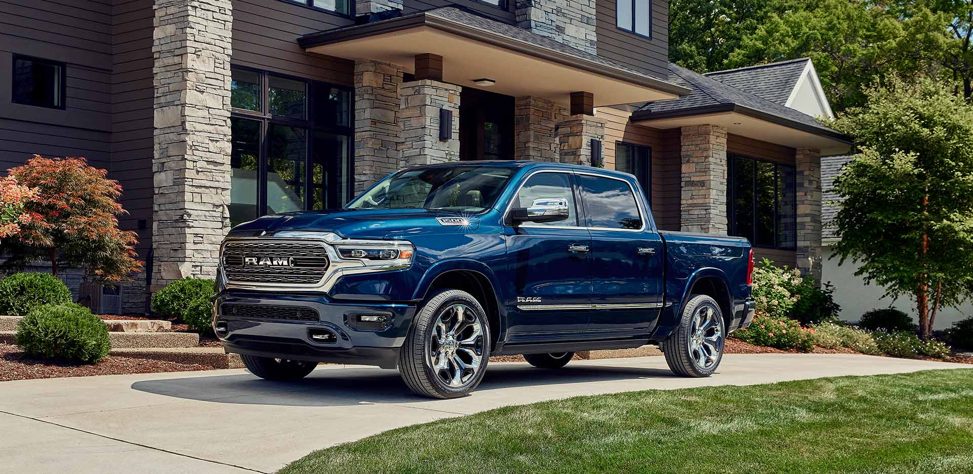 Display The 2023 Ram 1500 parked in the driveway of a large house.