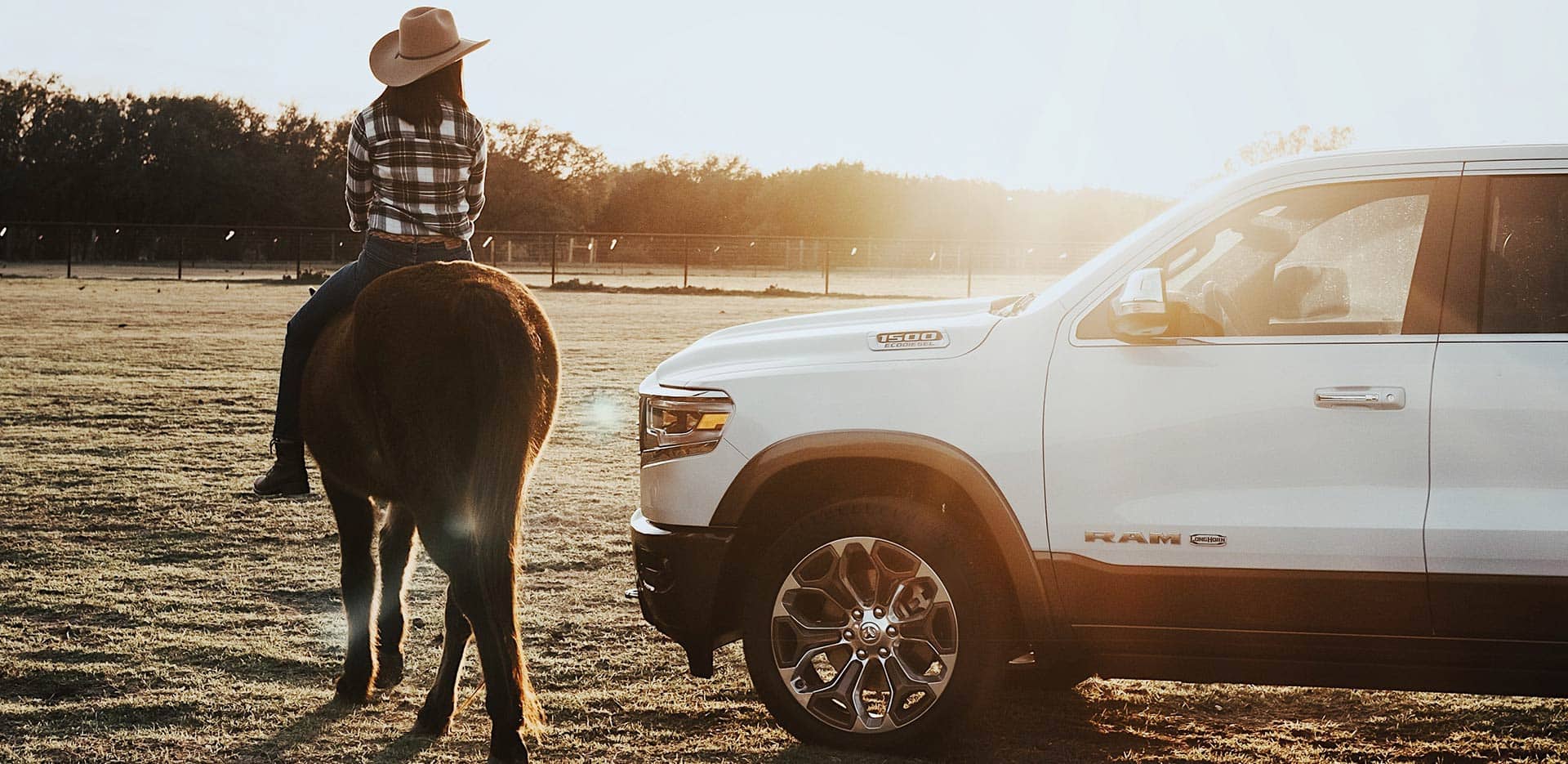 Display The 2023 Ram 1500 parked in a horse paddock with a woman on horseback beside it.