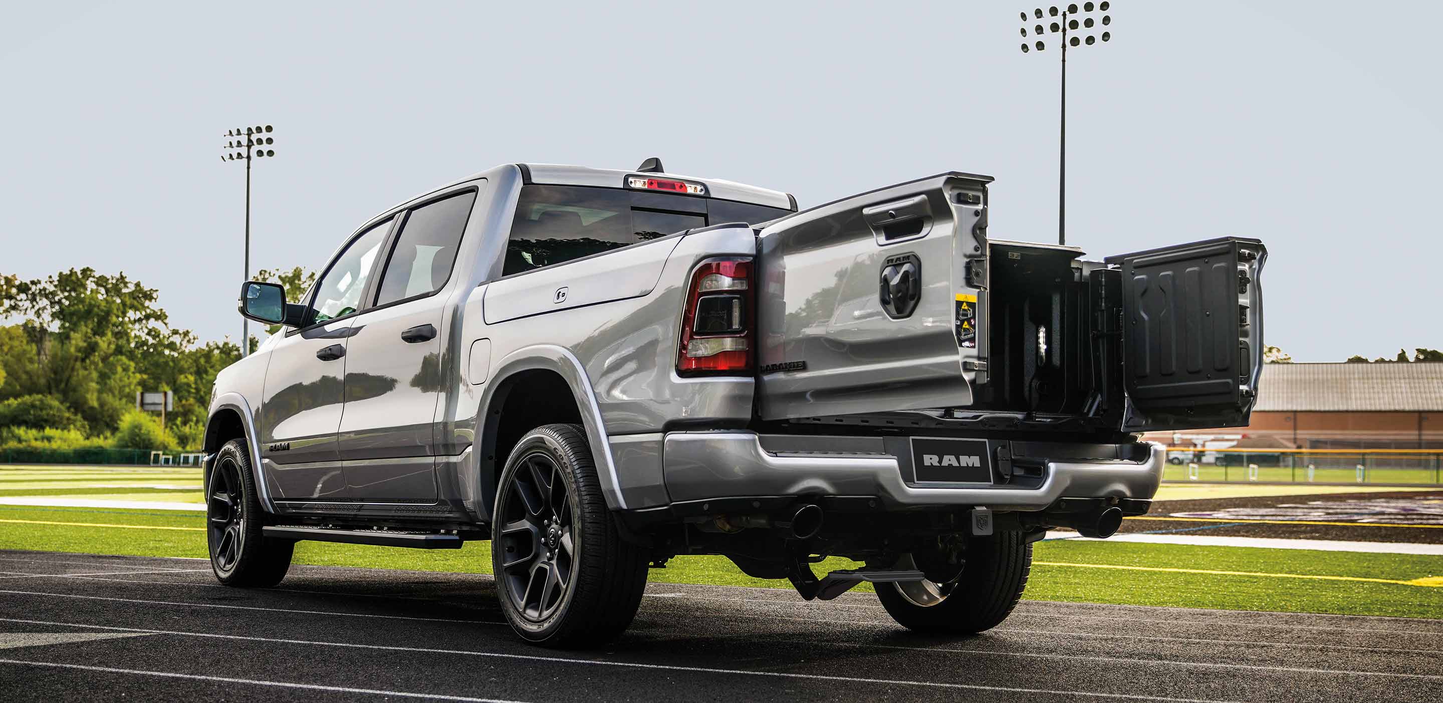 The 2023 Ram 1500 parked on a racetrack with the swing-open tailgate doors open.