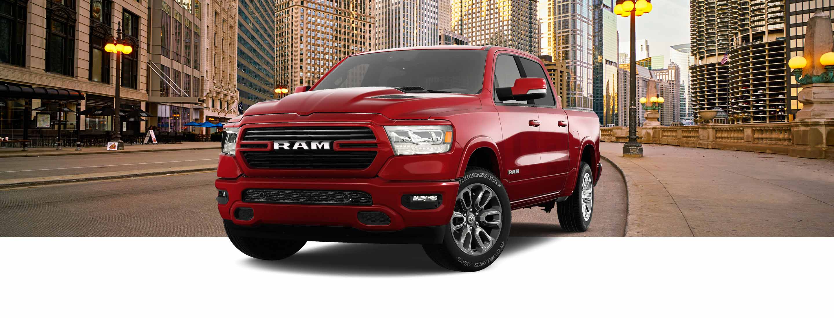 A red 2023 Ram 1500 Laramie Crew Cab with the Sport Appearance Package on a backdrop of a metropolitan city street.